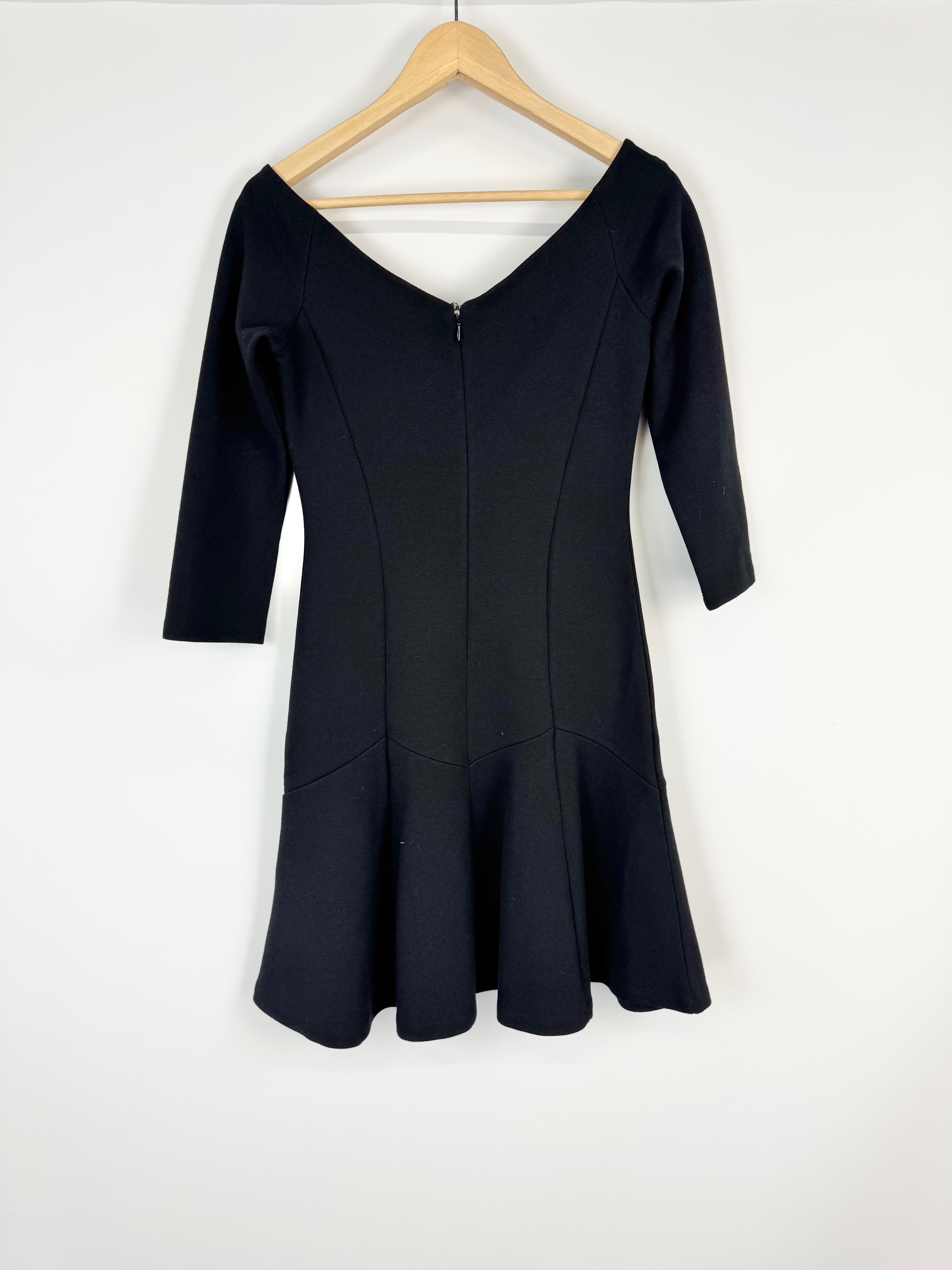 Black dress on a wooden hanger against a white background