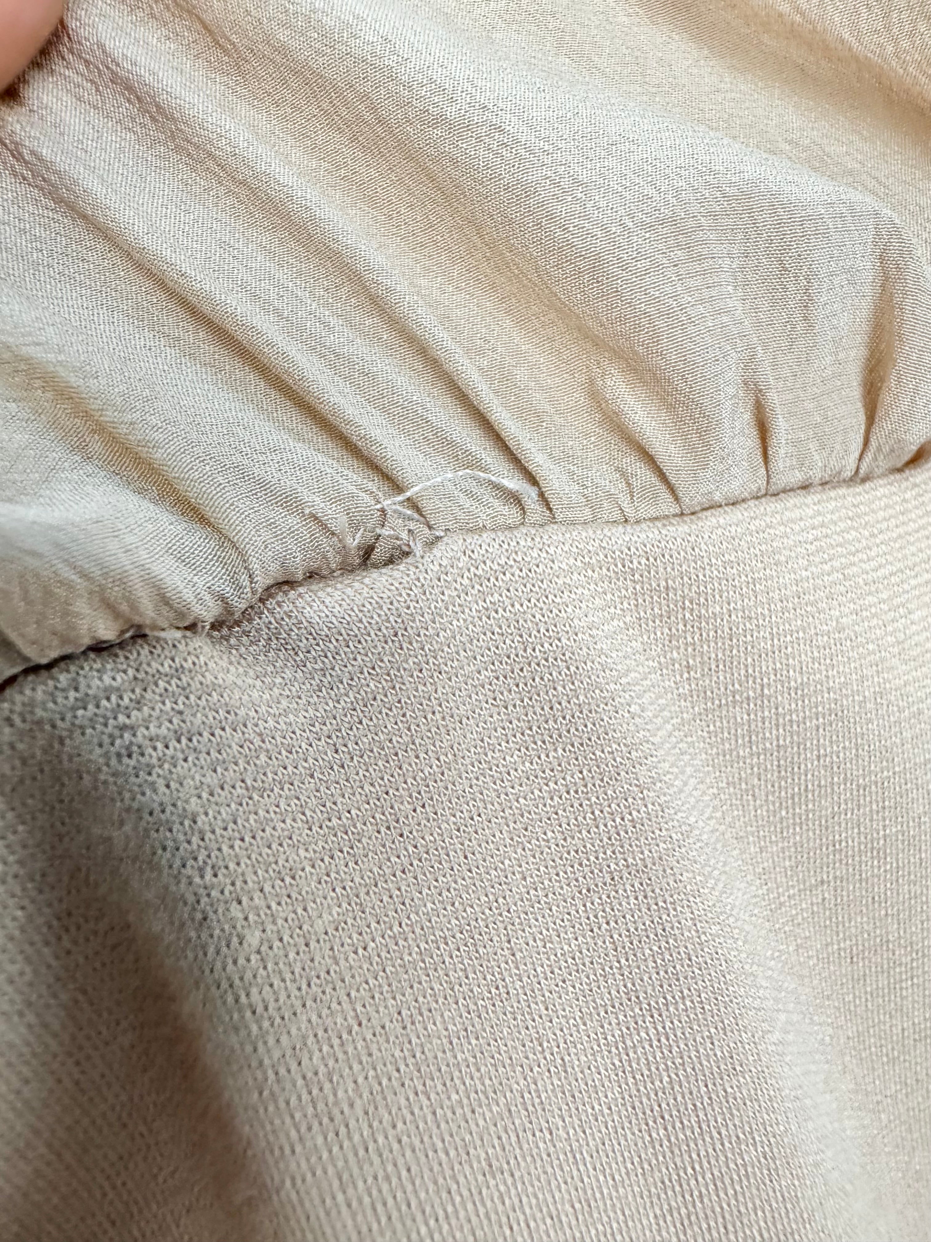 Close-up of beige fabric with a focus on texture and stitching.