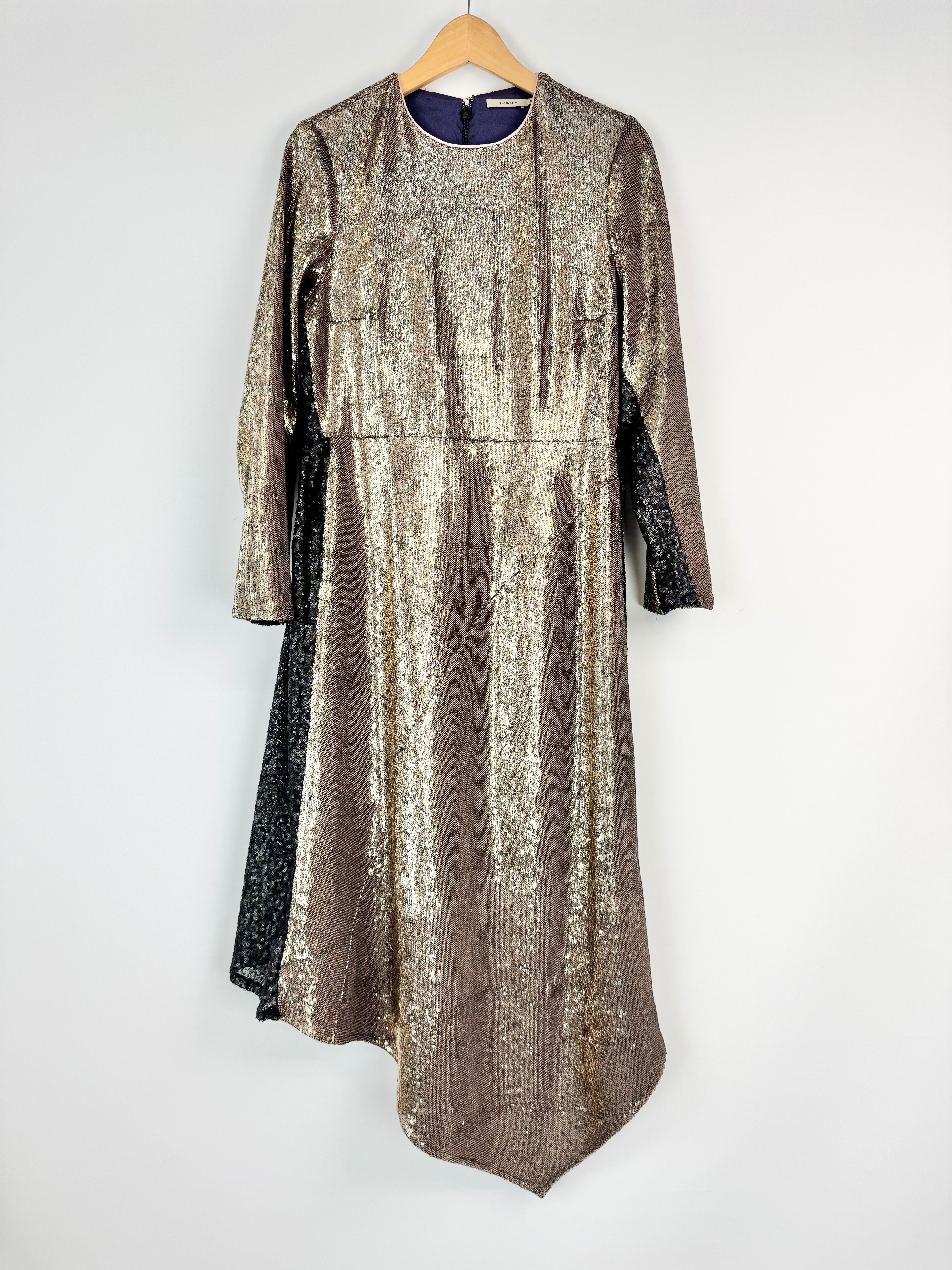 Gold sequin dress on a hanger against a white background