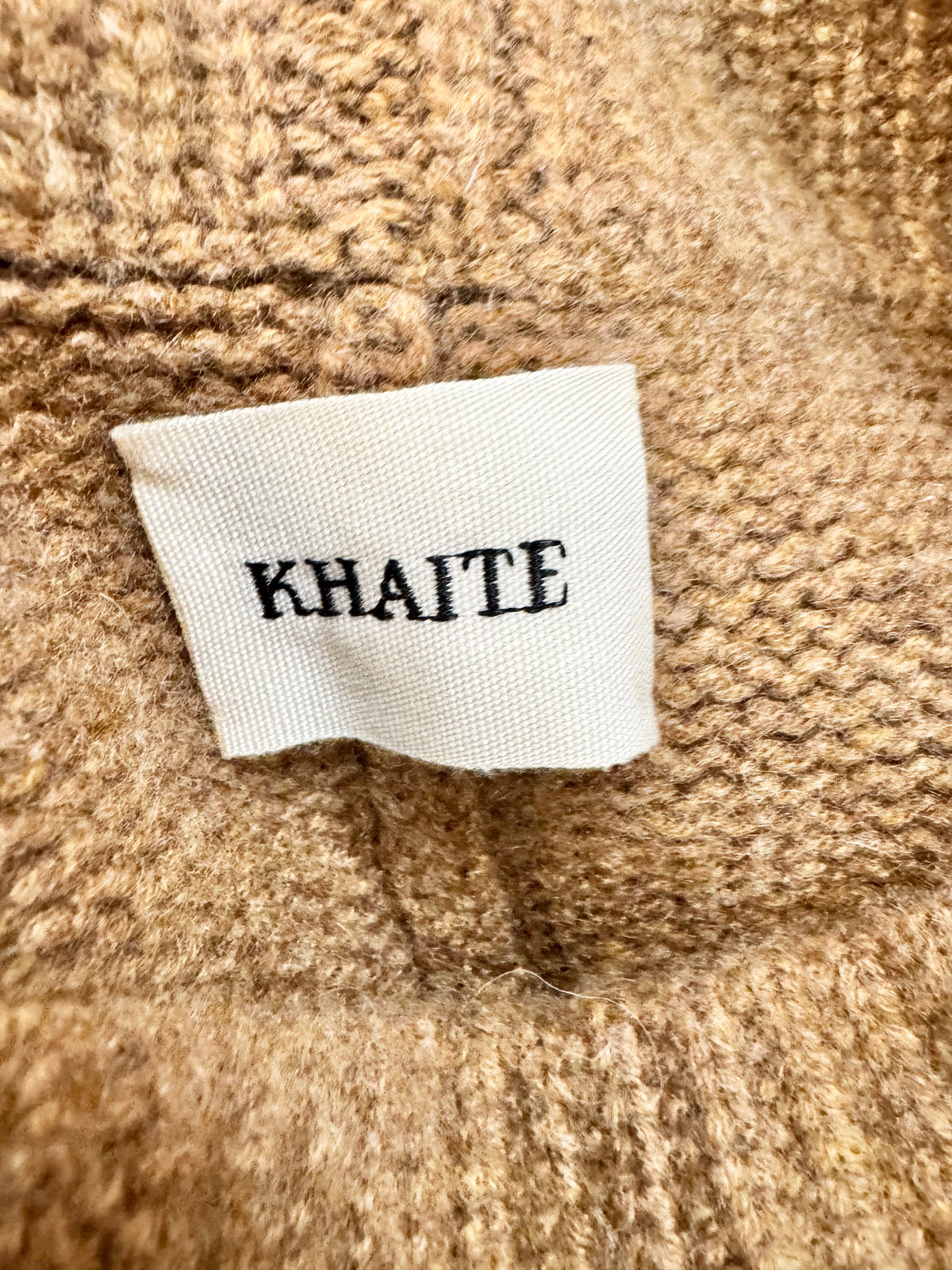 Close-up of a 'KHAITE' label on a textured fabric background