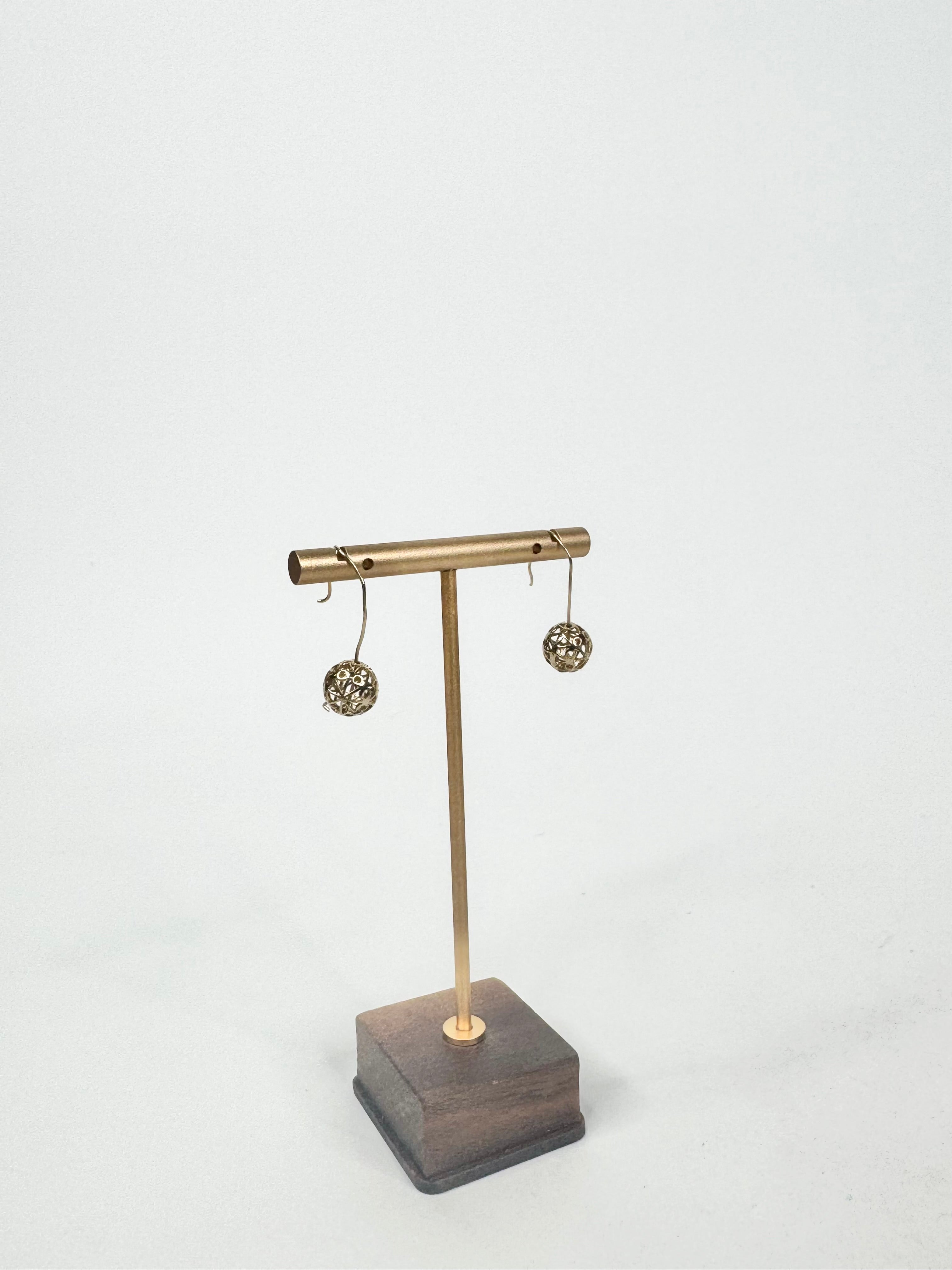 Brass earring stand with wooden base on a white background