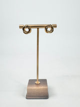 Gold earring stand with a square base on a white background