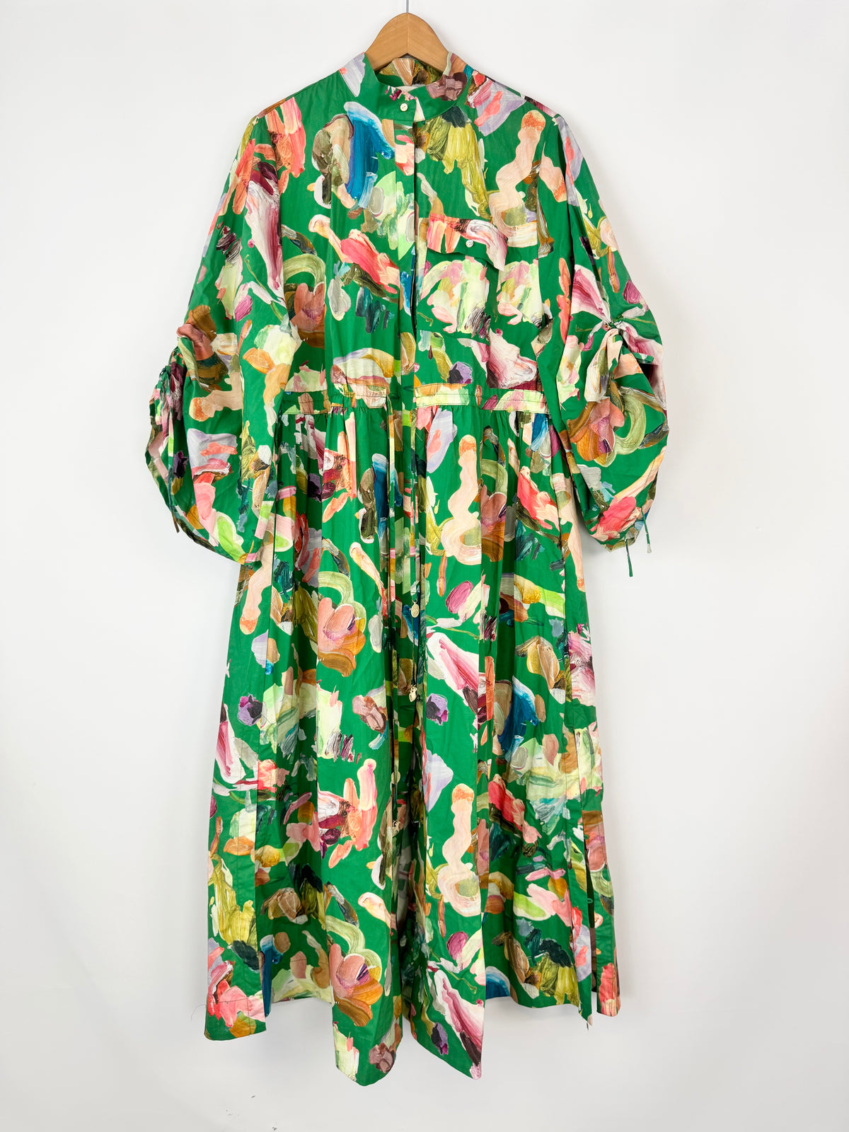 Colorful floral dress on a wooden hanger against a white background