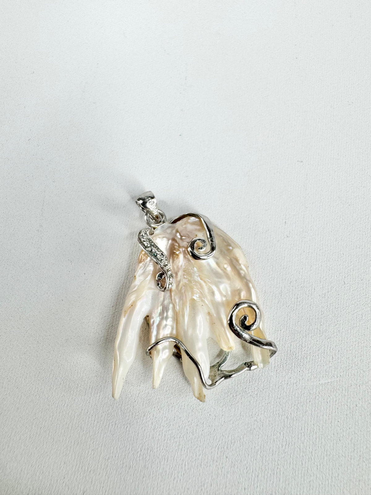 Silver pendant with a shell design on a light gray background