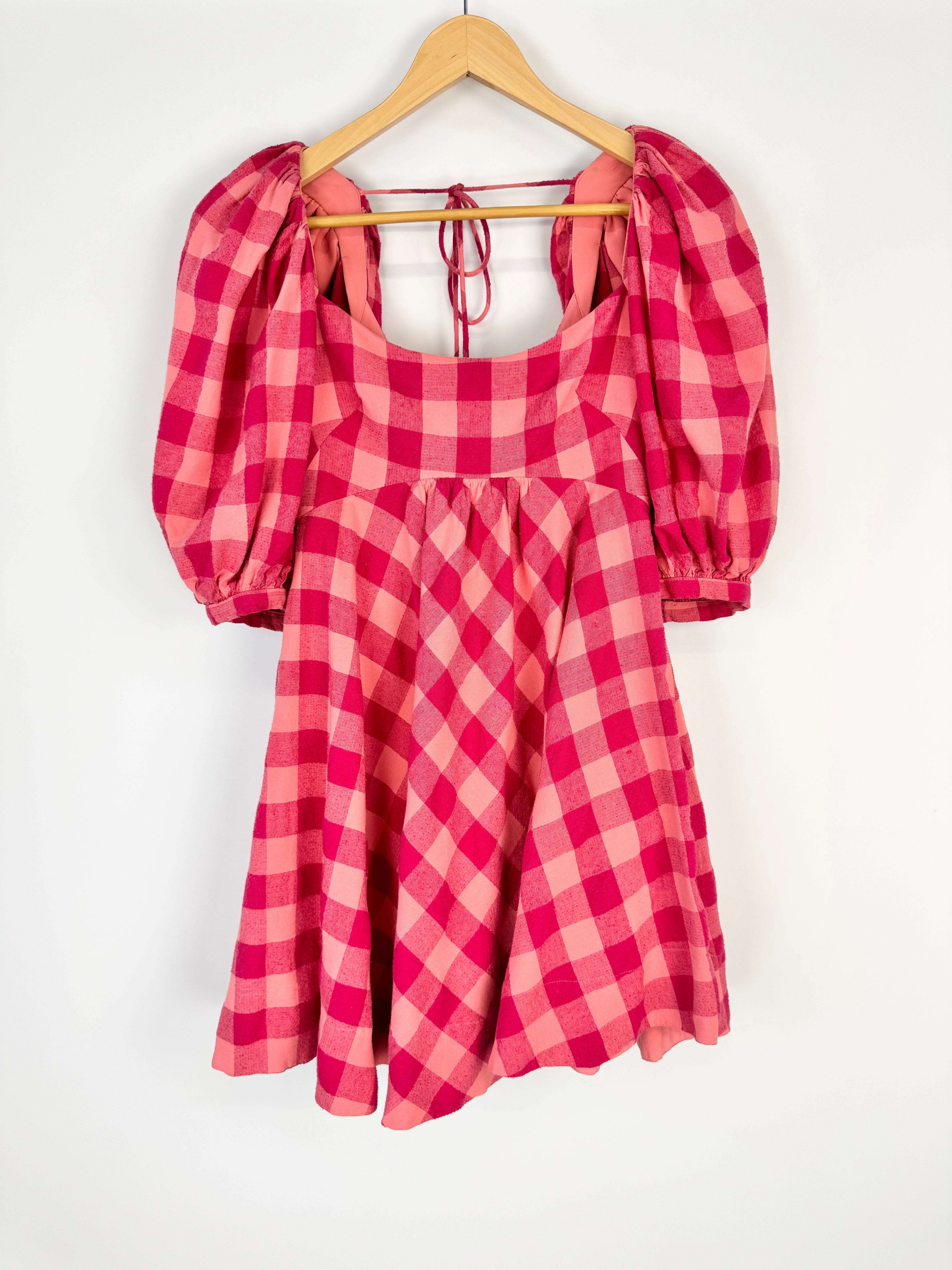 Red and white checkered dress with puff sleeves on a hanger against a white background