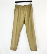 khaki pants hanging on a black rod against a white background