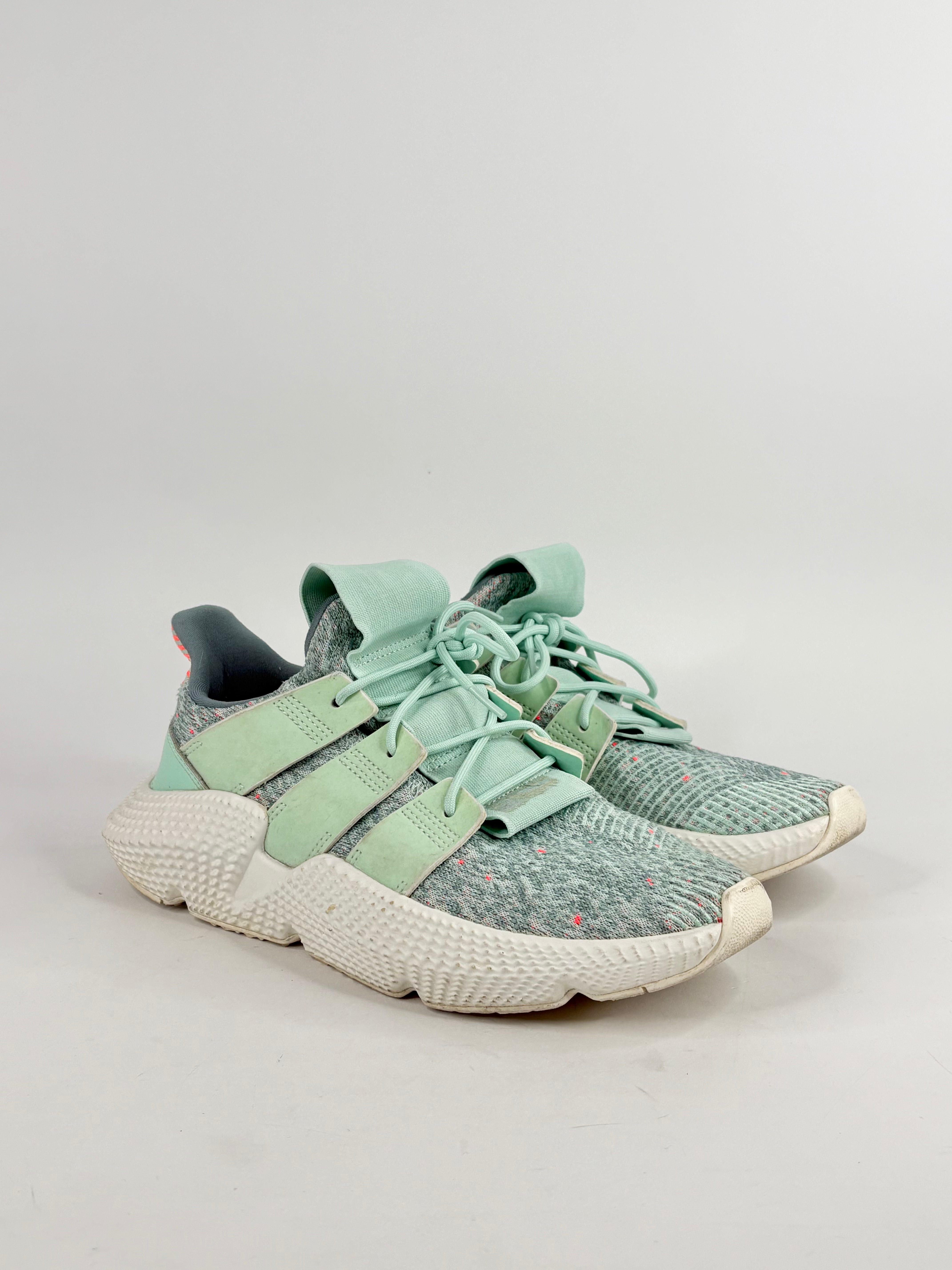 Pair of green Adidas sneakers on a light gray background