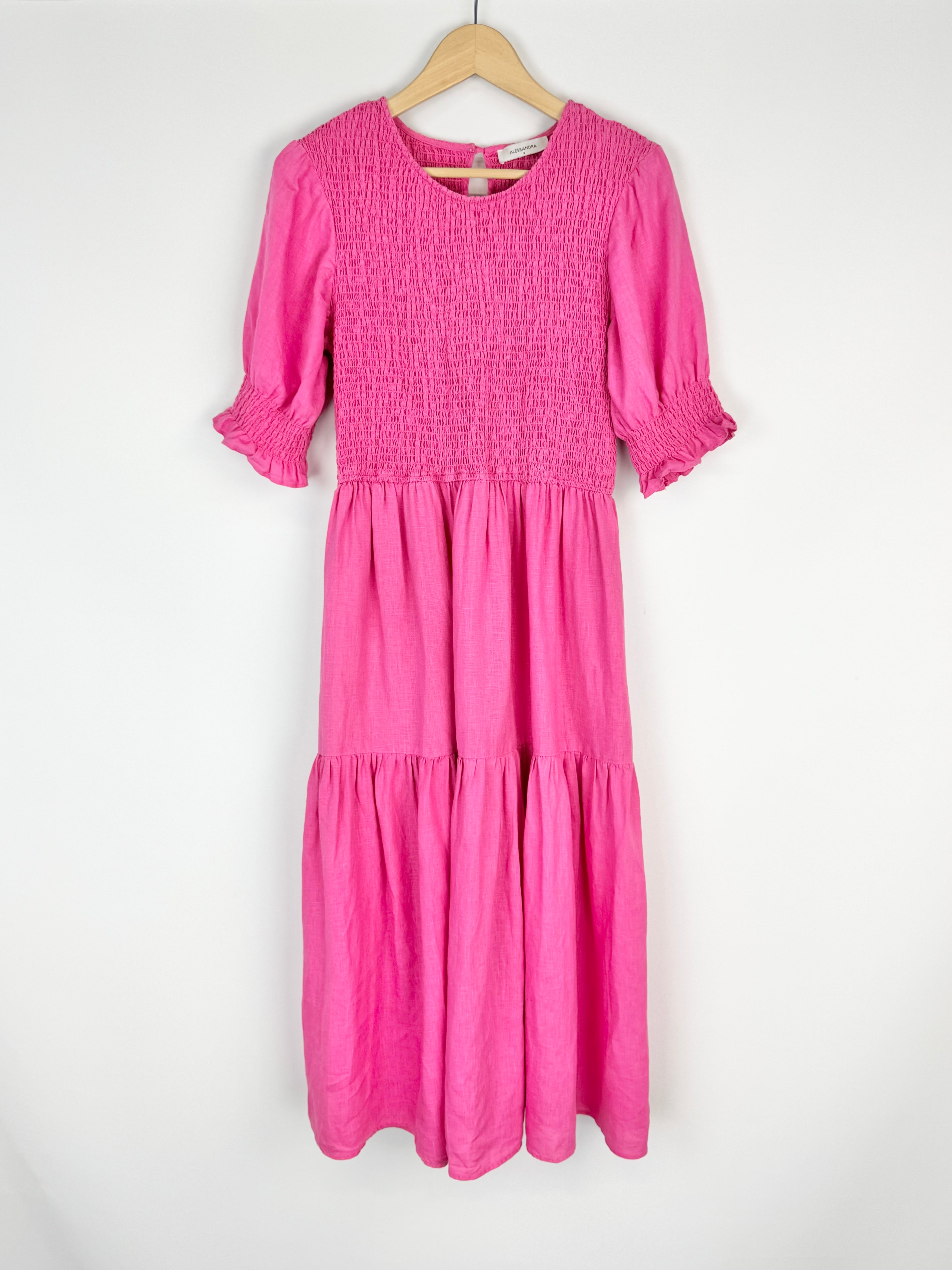Pink dress on a hanger against a white background