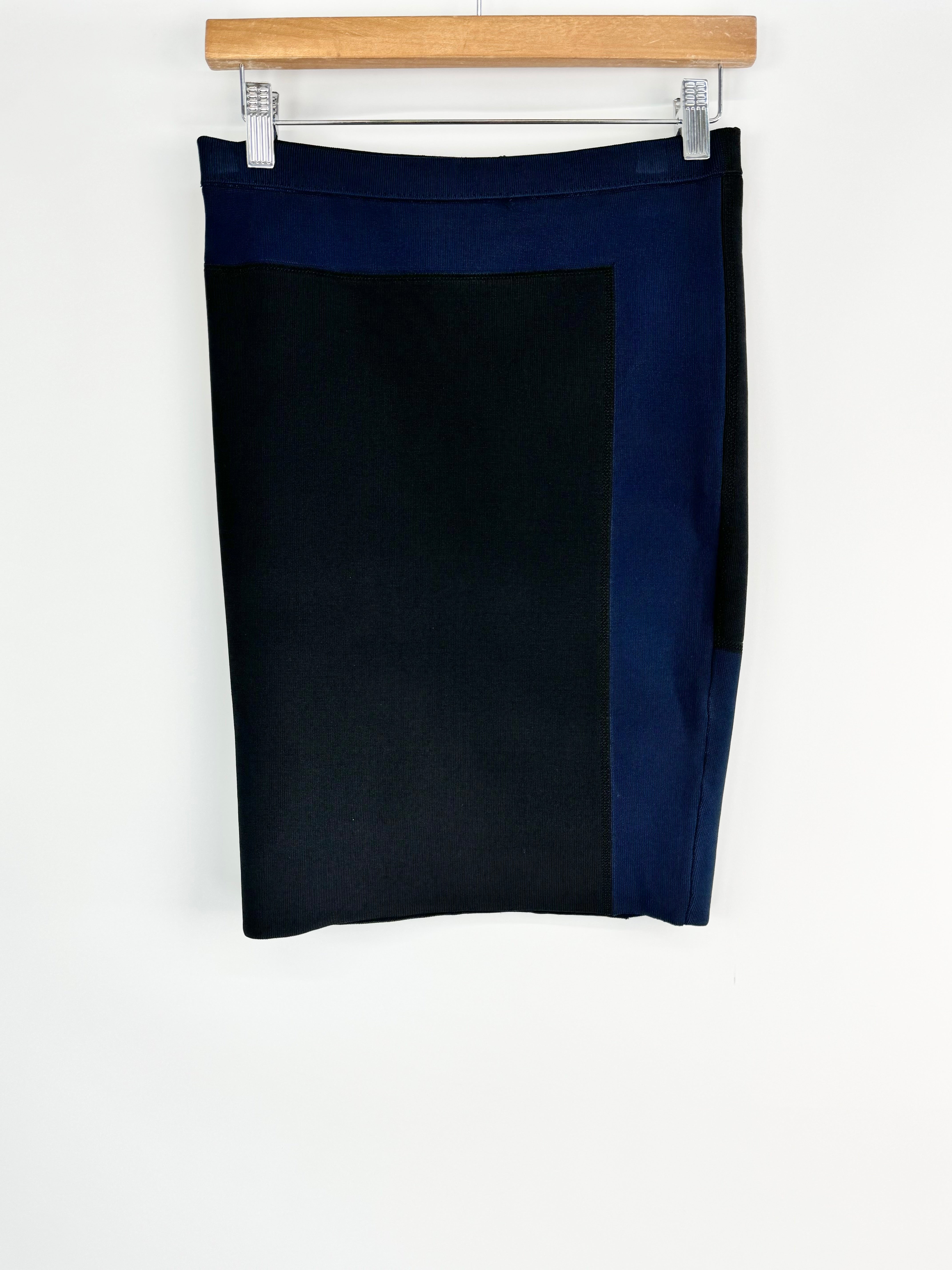 Black skirt hanging on a wooden hanger against a white background