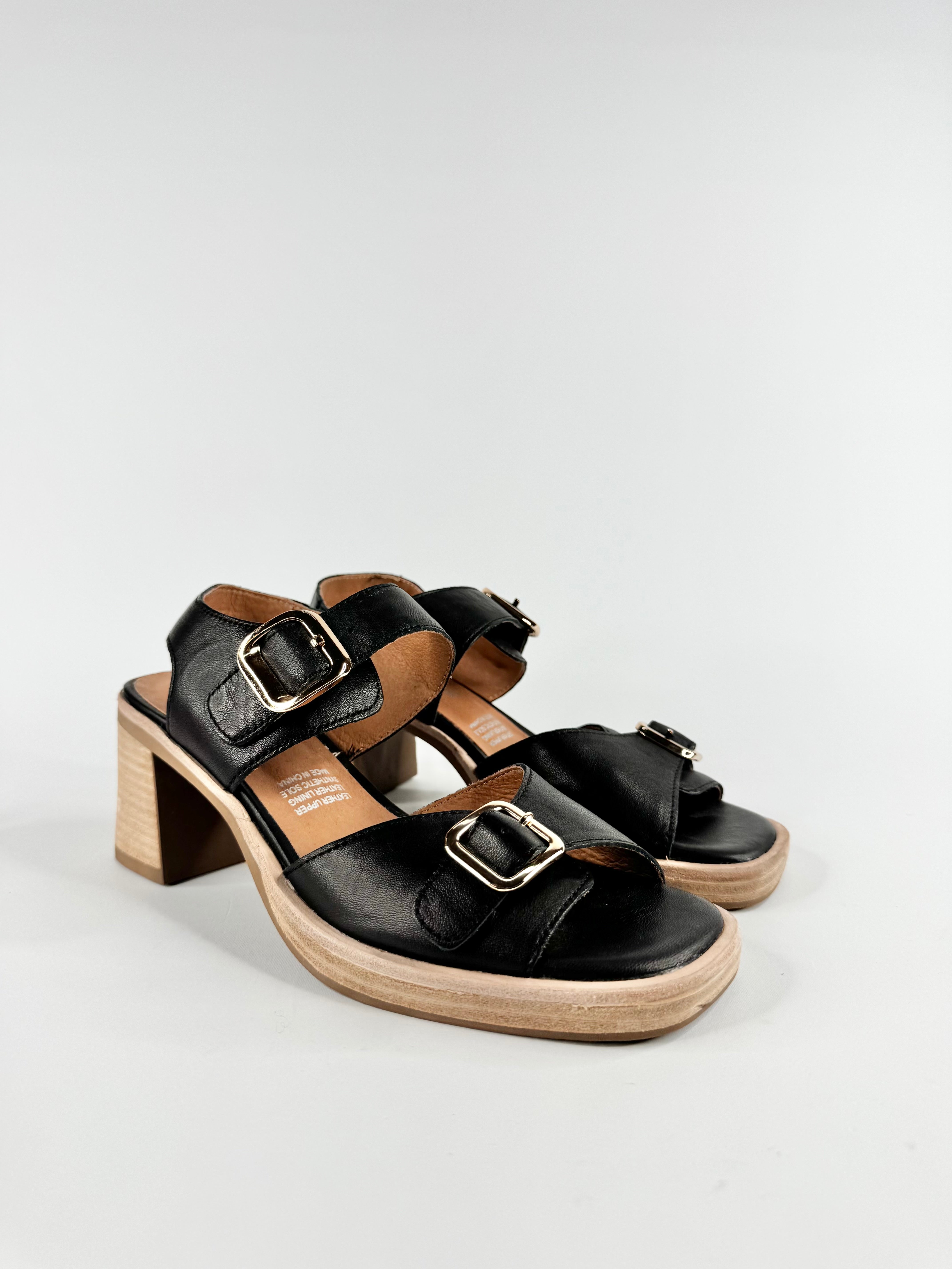 Black sandals with wooden block heel on a light gray background