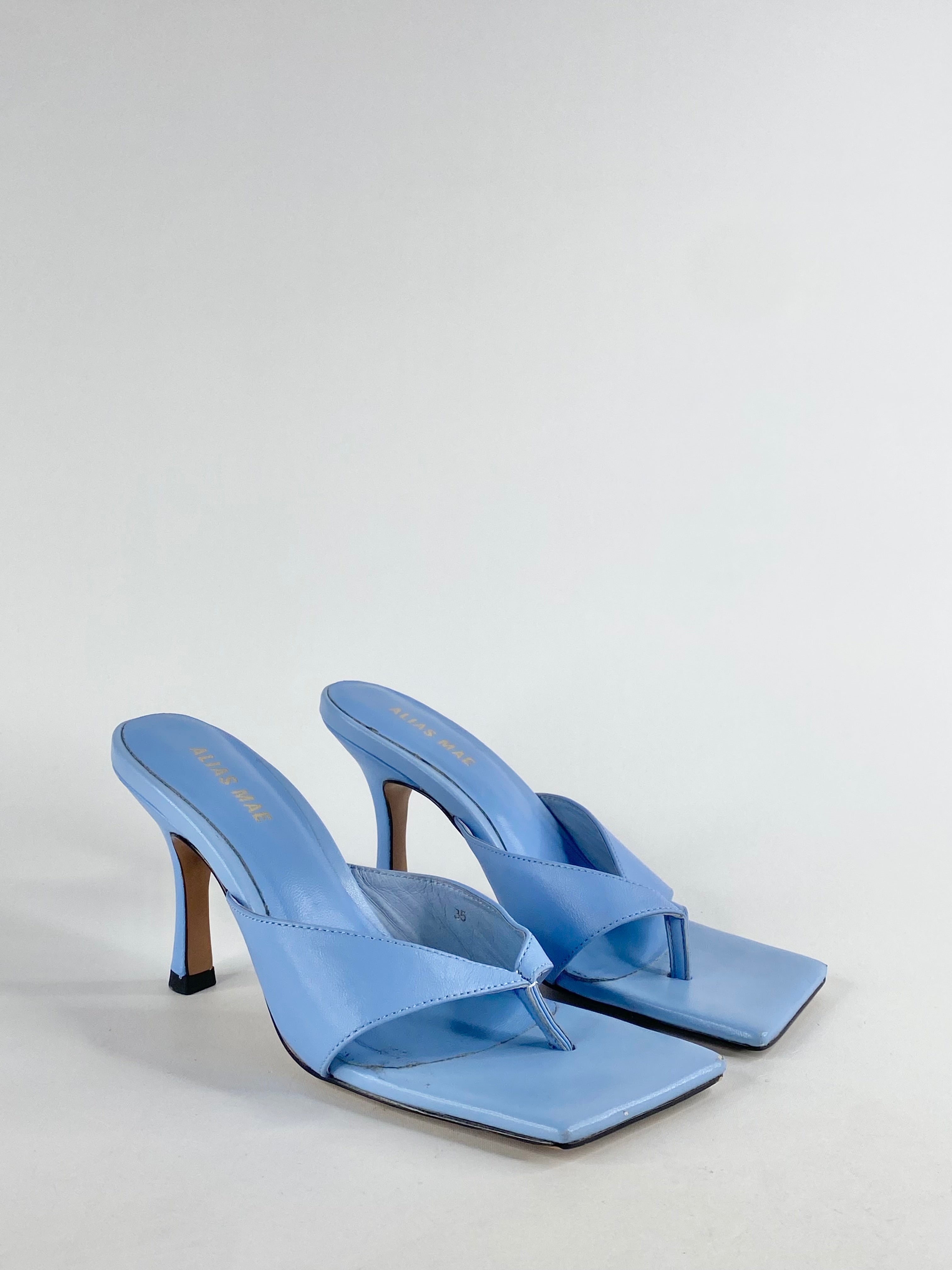 A pair of blue kitten heel thongs with a squared toe, showing signs of wear on the soles.