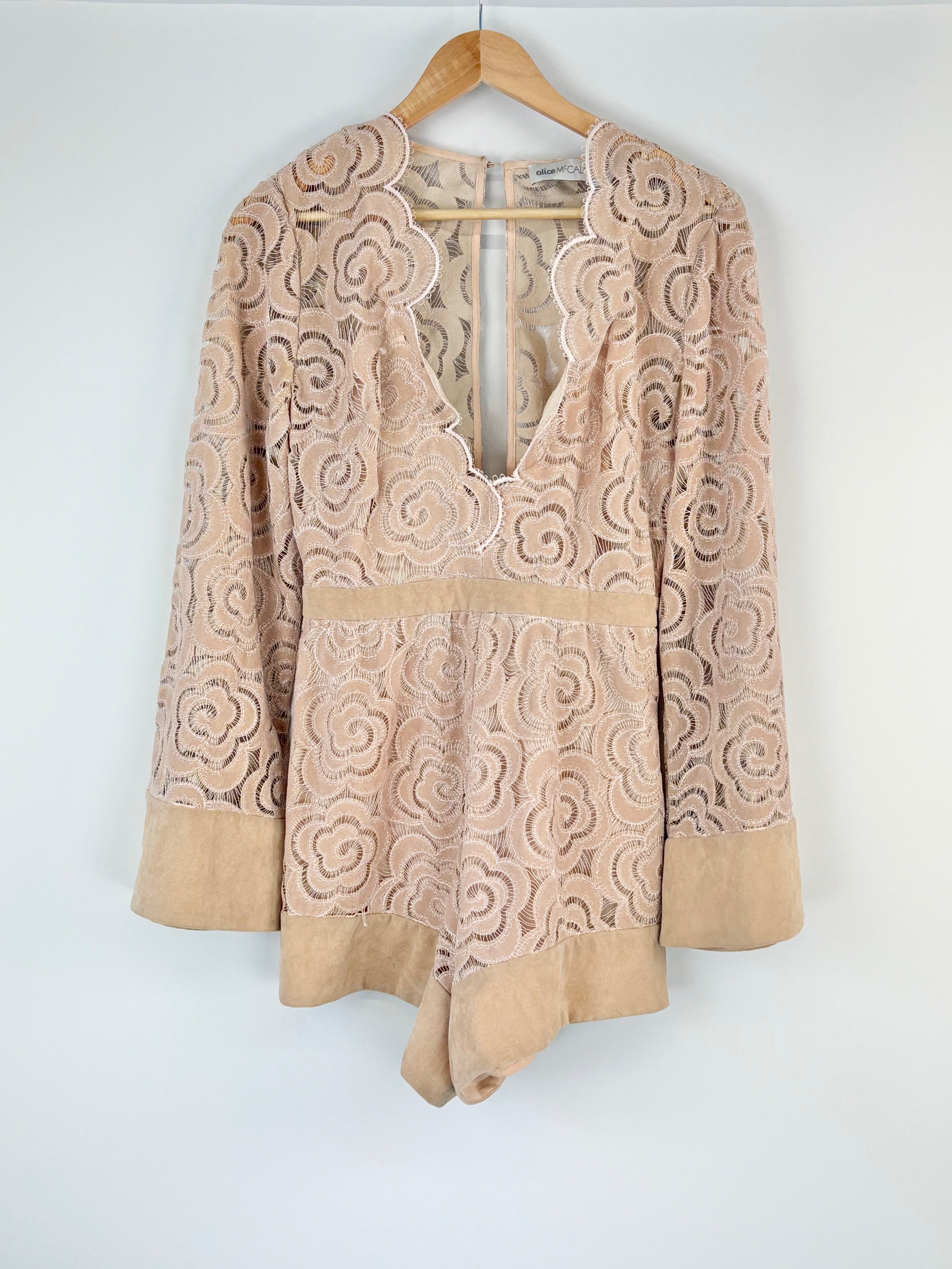 Beige lace top on a wooden hanger against a white background