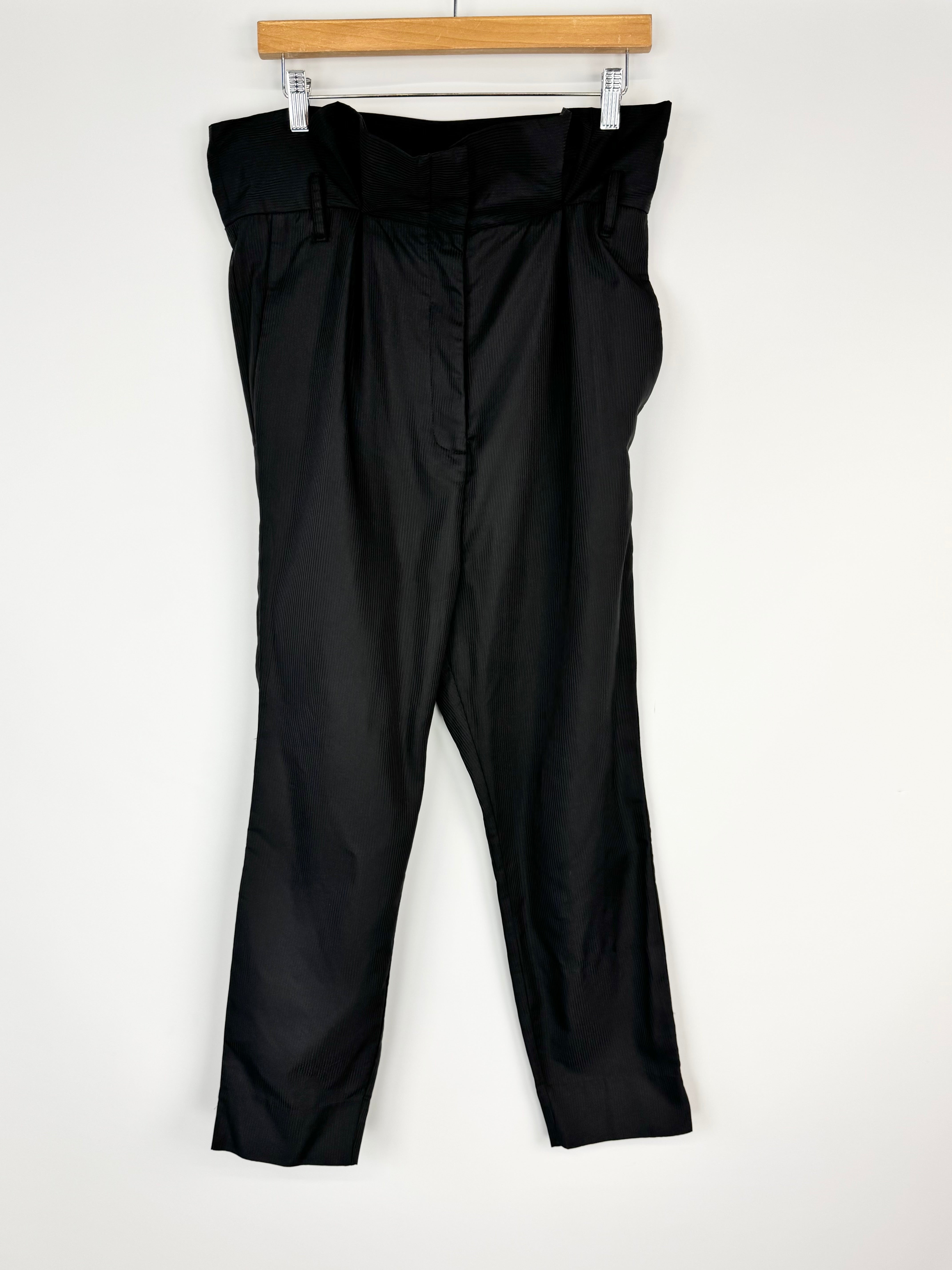 Black pants hanging on a wooden hanger against a white background