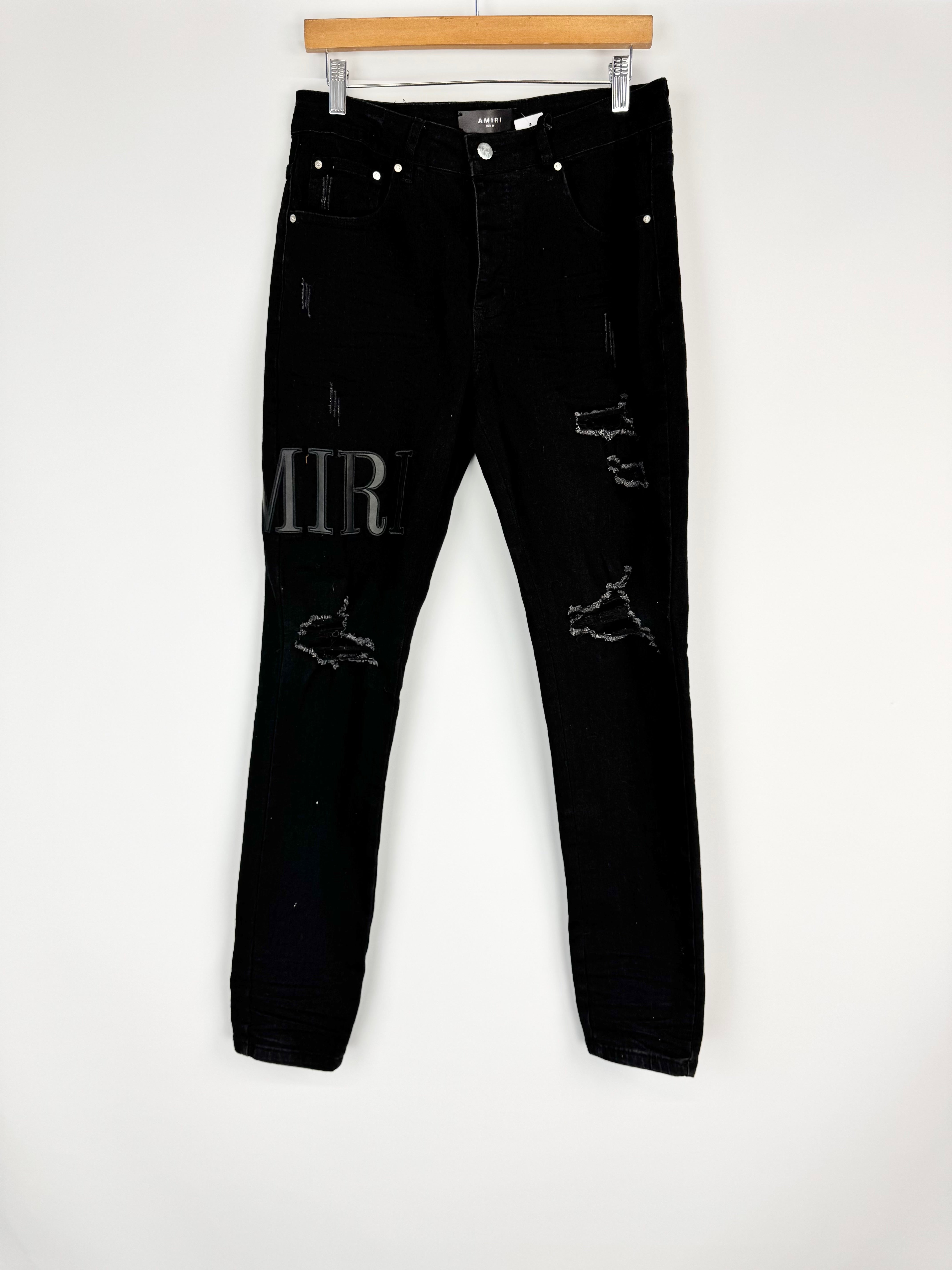 Black distressed jeans on a white background