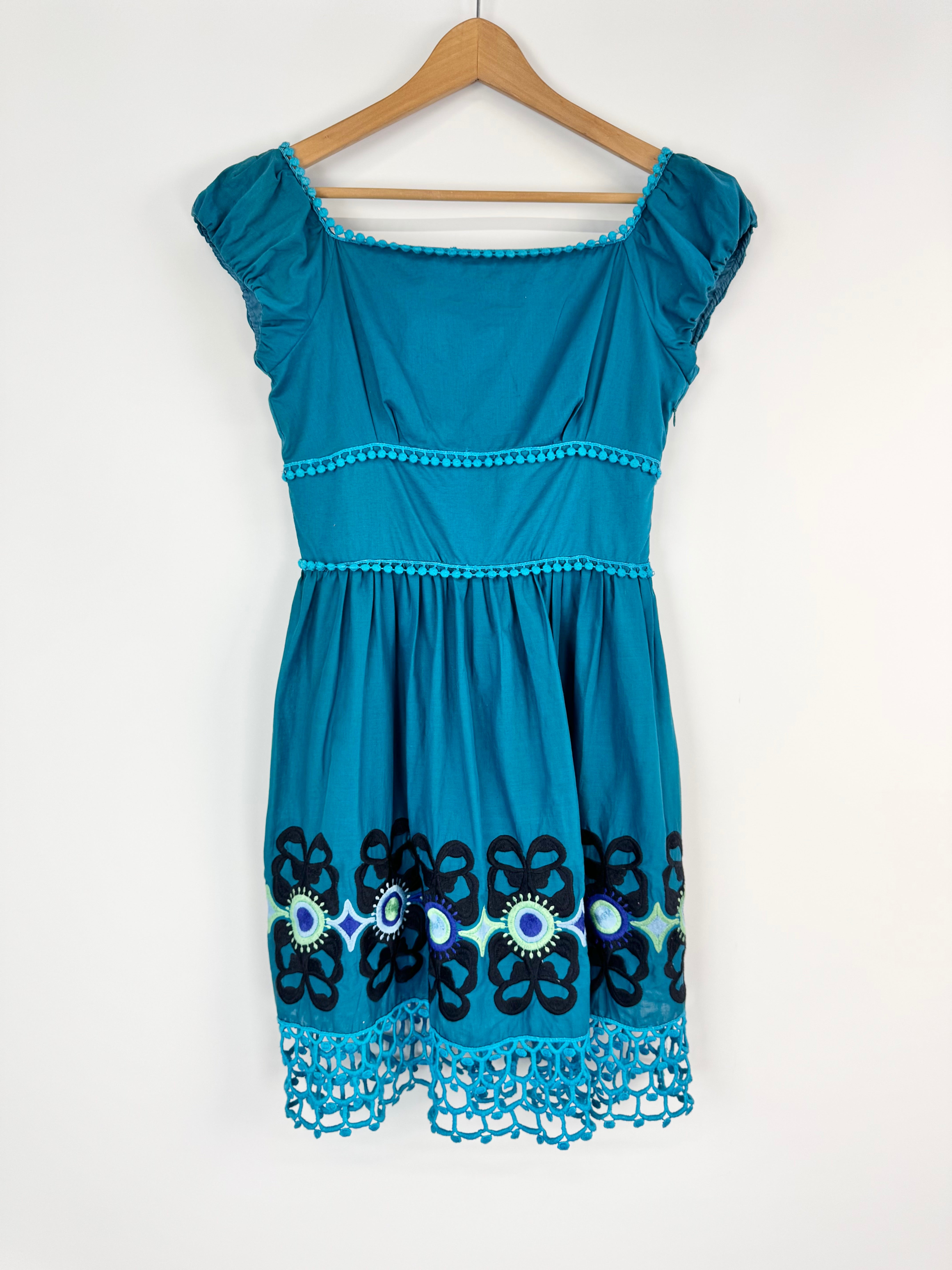 Blue dress with lace details on a hanger against a white background