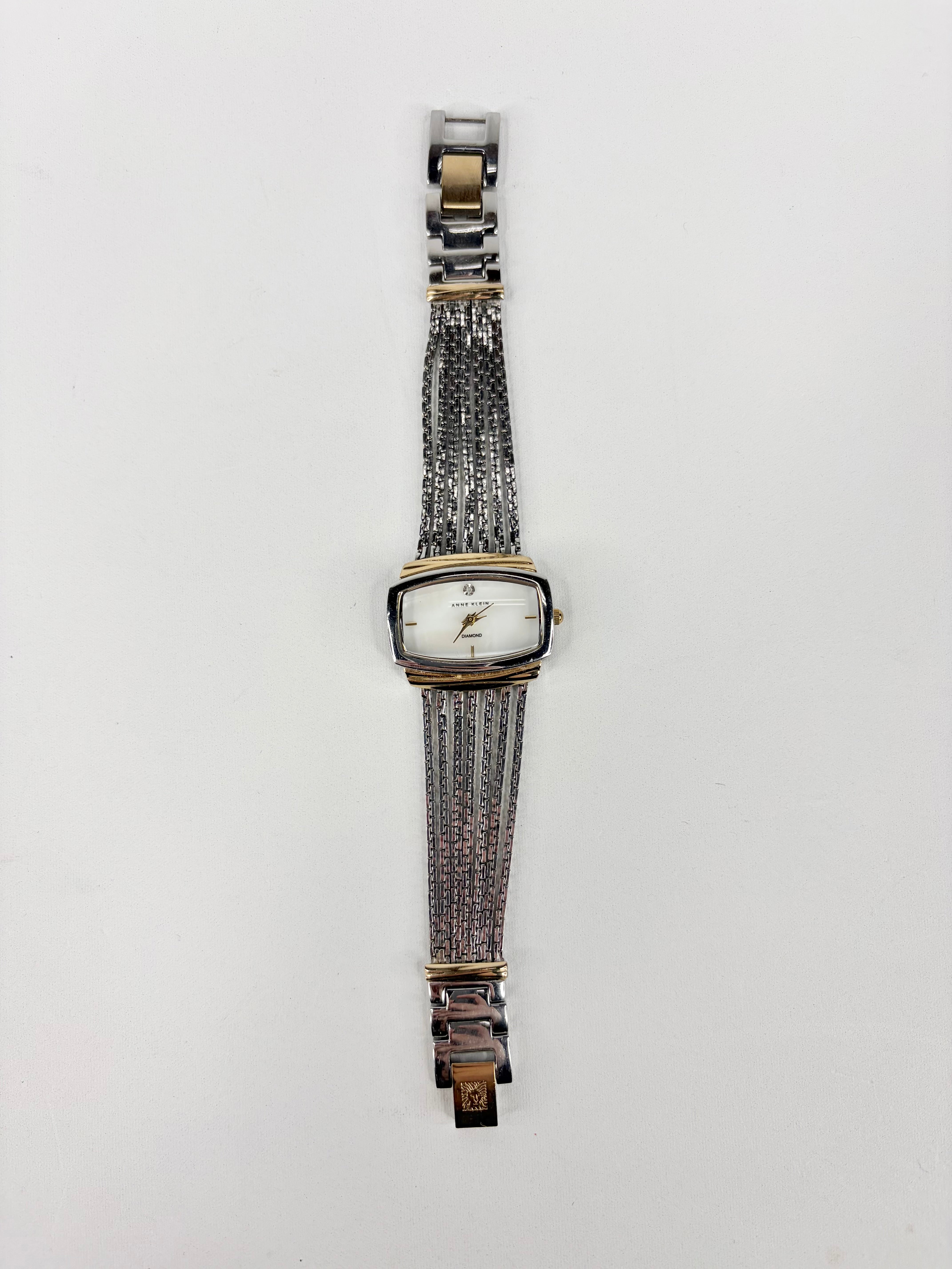 Wristwatch with a silver and gold mesh strap on a white background