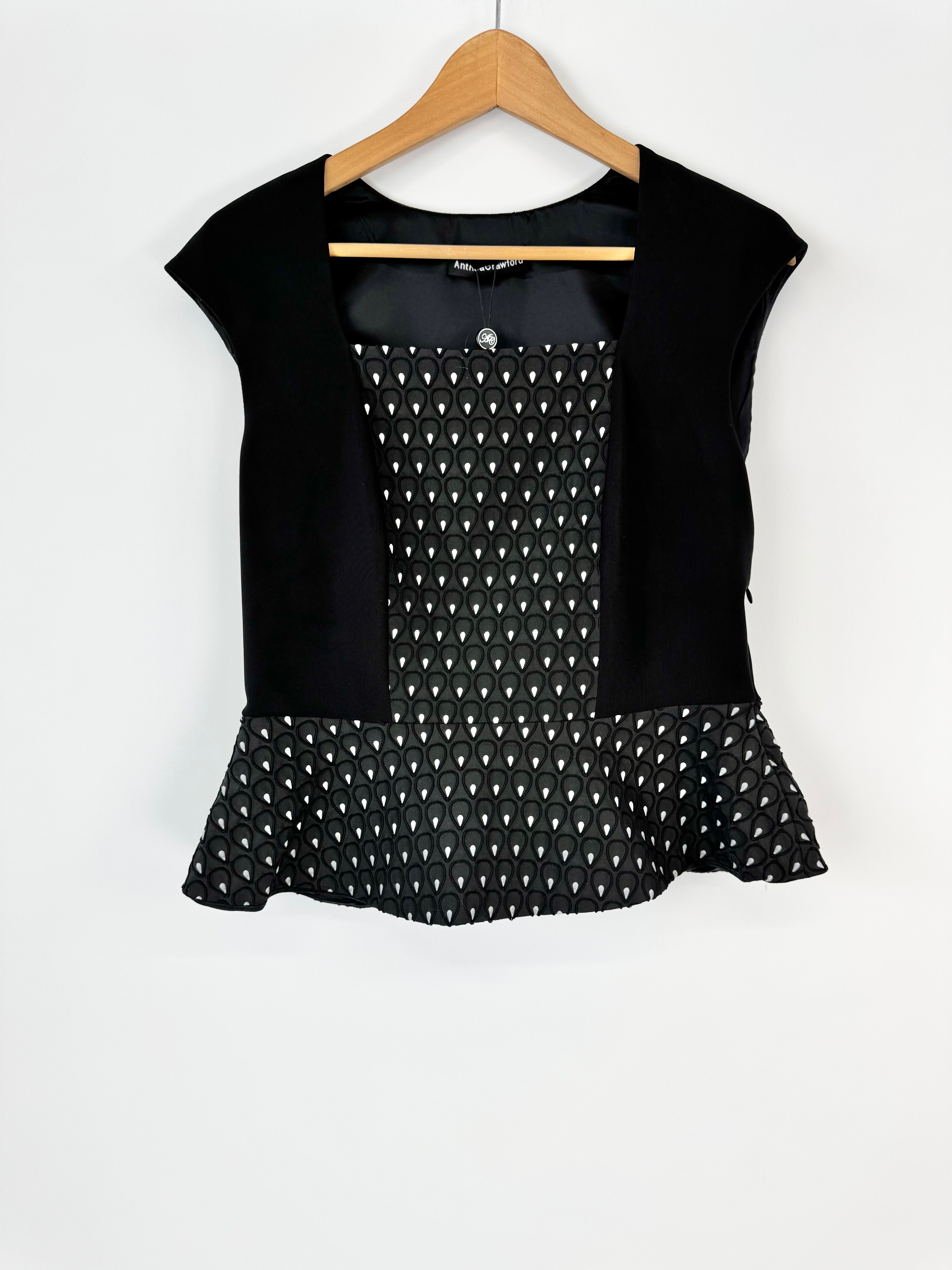 Black top with white pattern on a hanger against a white background