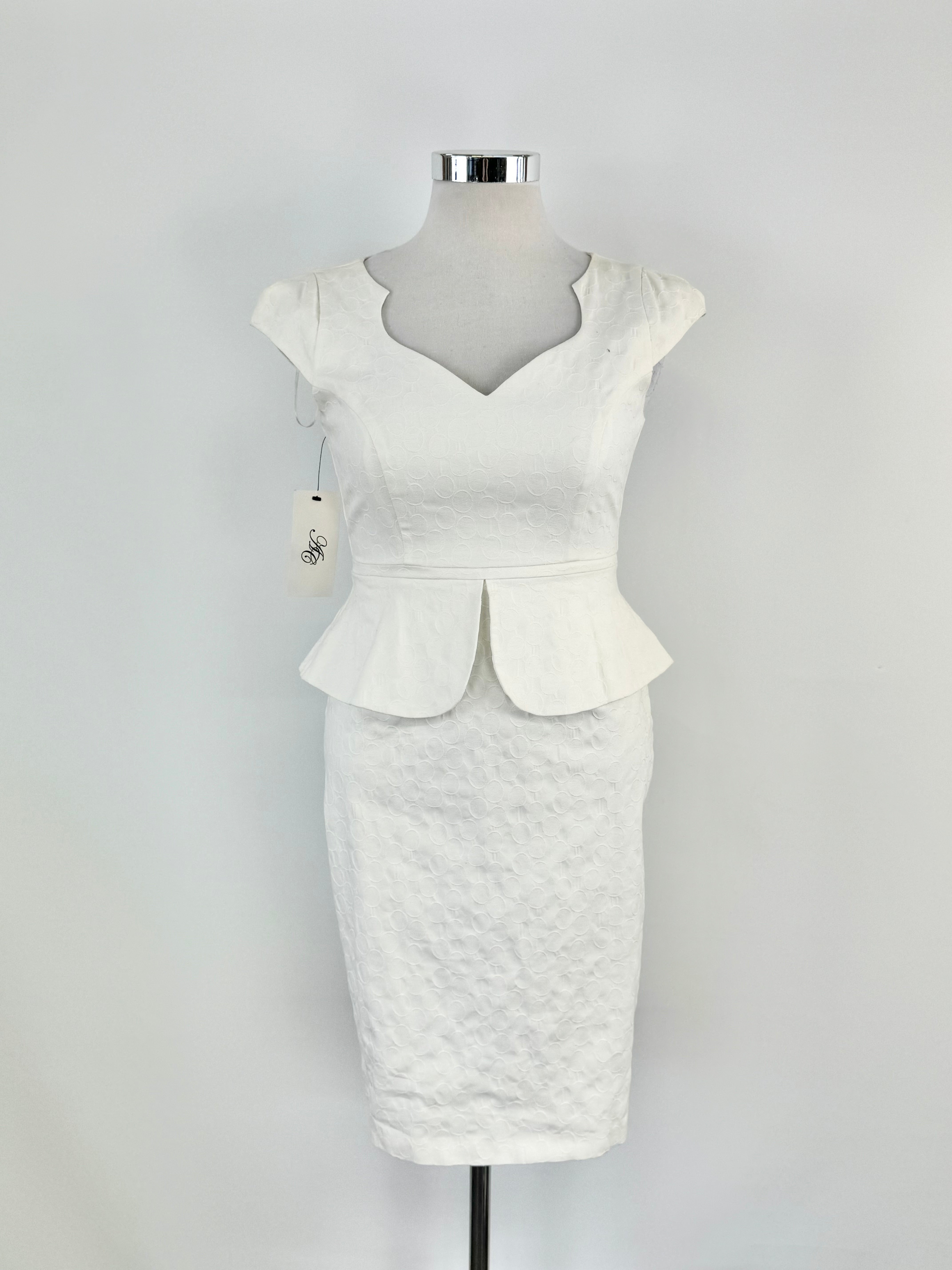 A white cream-colored dress with a sweetheart neckline, cap sleeves, and a peplum waist, displayed on a mannequin.