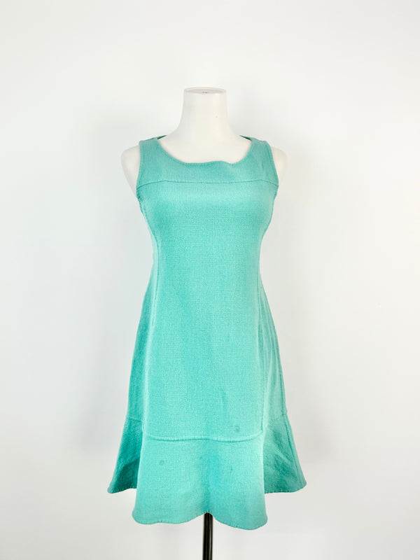 A seafoam green sheath dress on a mannequin, with a knee-length cut and sleeveless design.