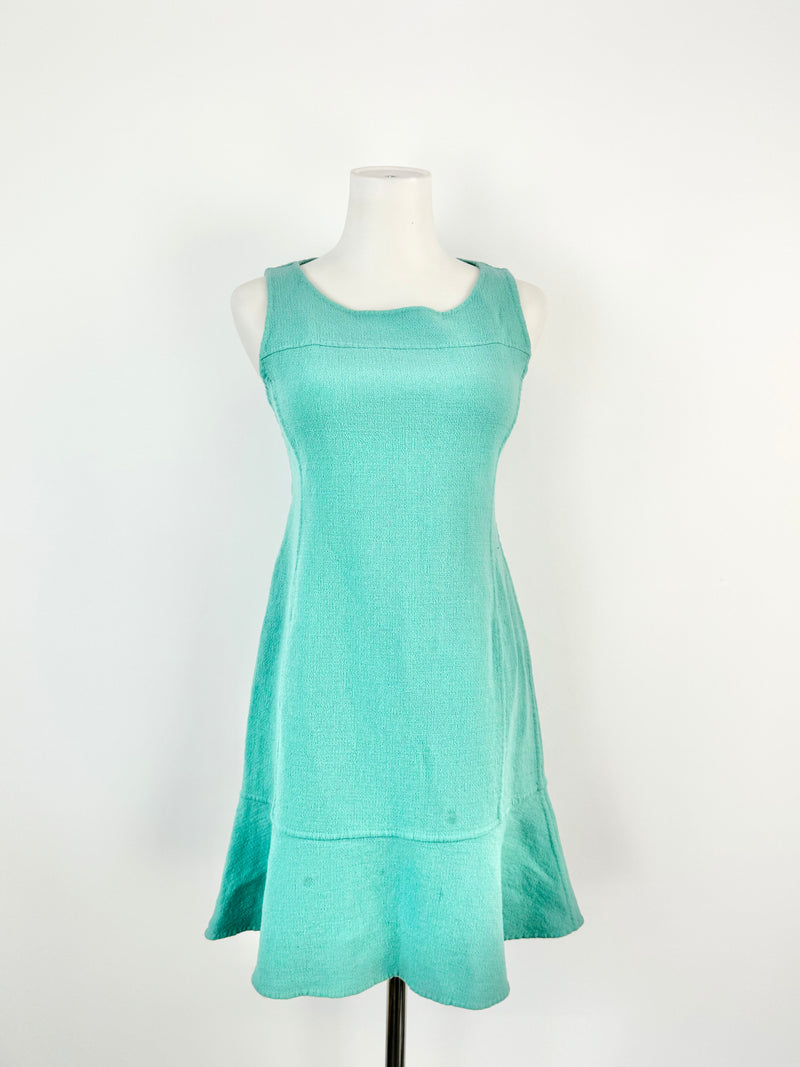 A seafoam green sheath dress on a mannequin, with a knee-length cut and sleeveless design.