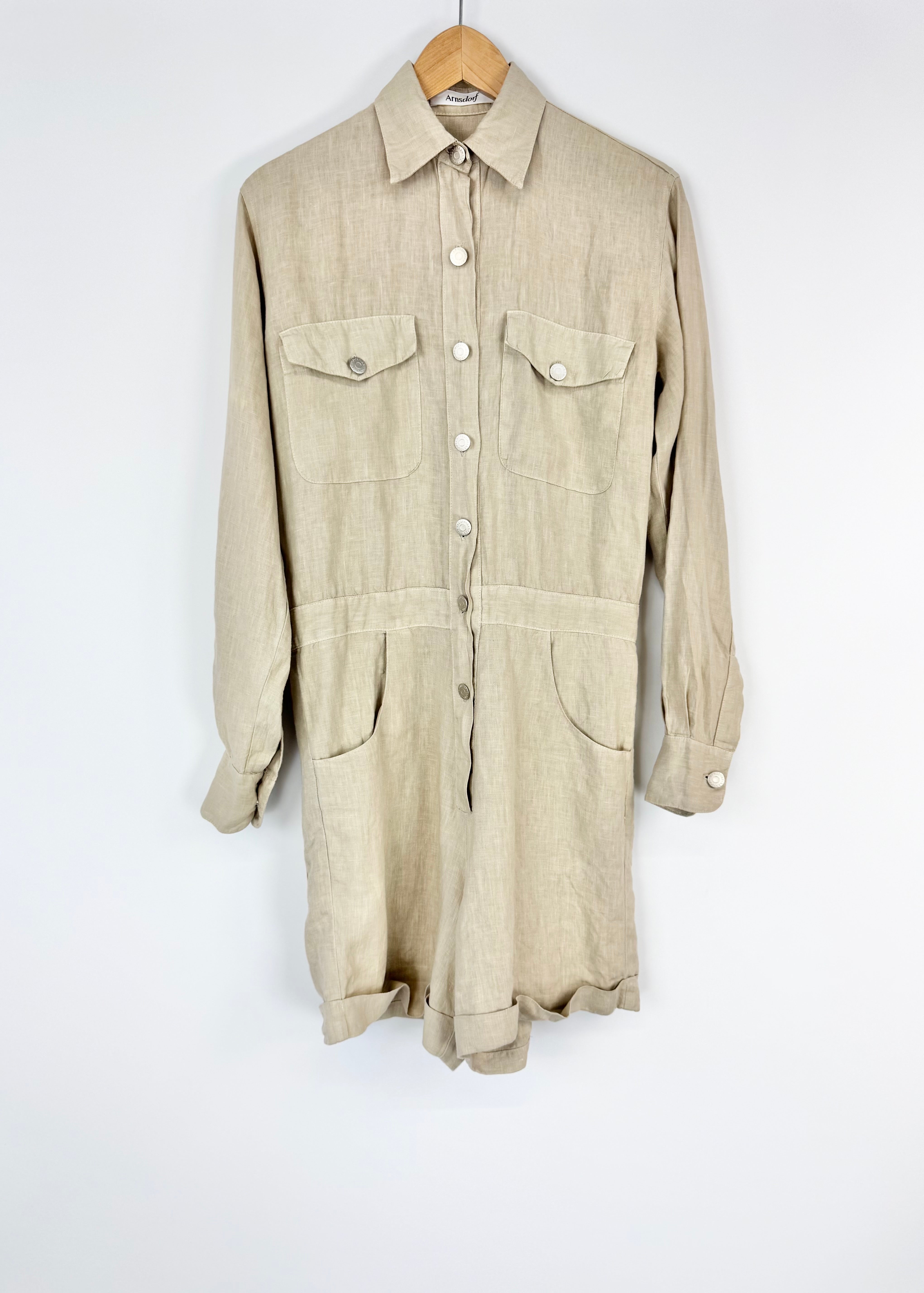 Beige work jumpsuit on a hanger against a white background