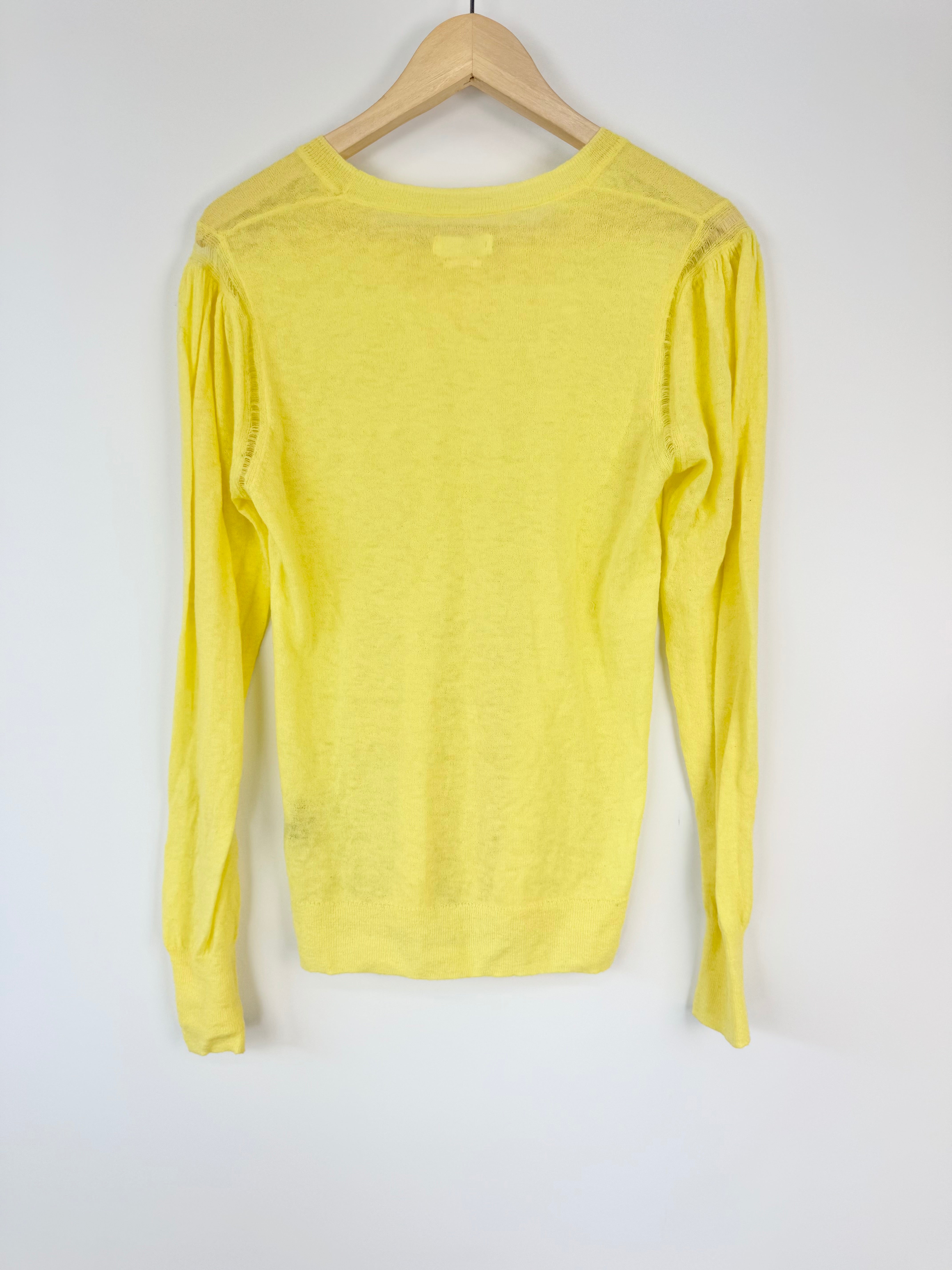 Yellow long-sleeve top on a wooden hanger against a white background