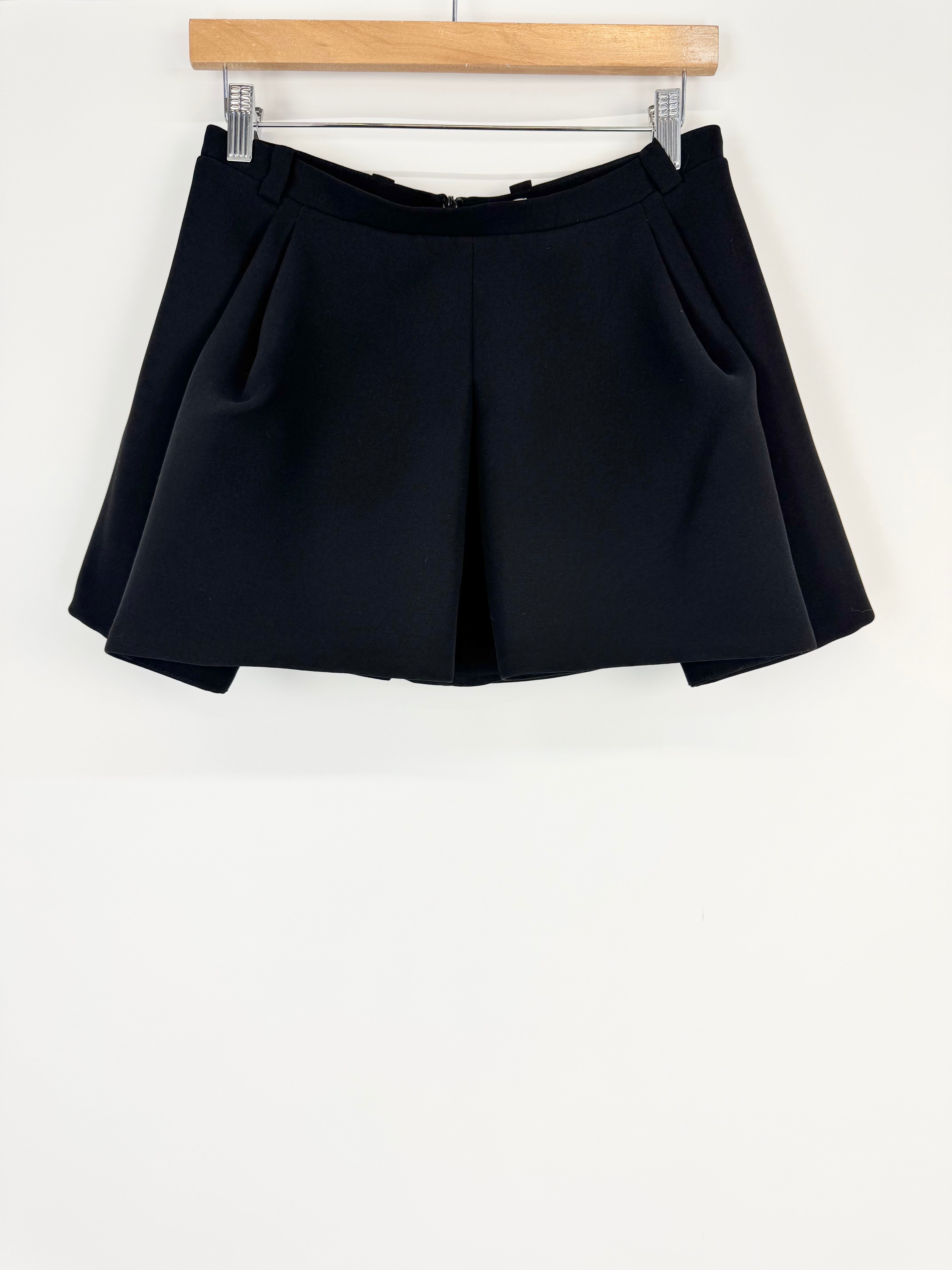 Black skirt hanging on a wooden hanger against a white background