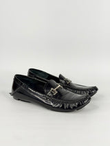 Black patent leather loafers with decorative buckles on a white background