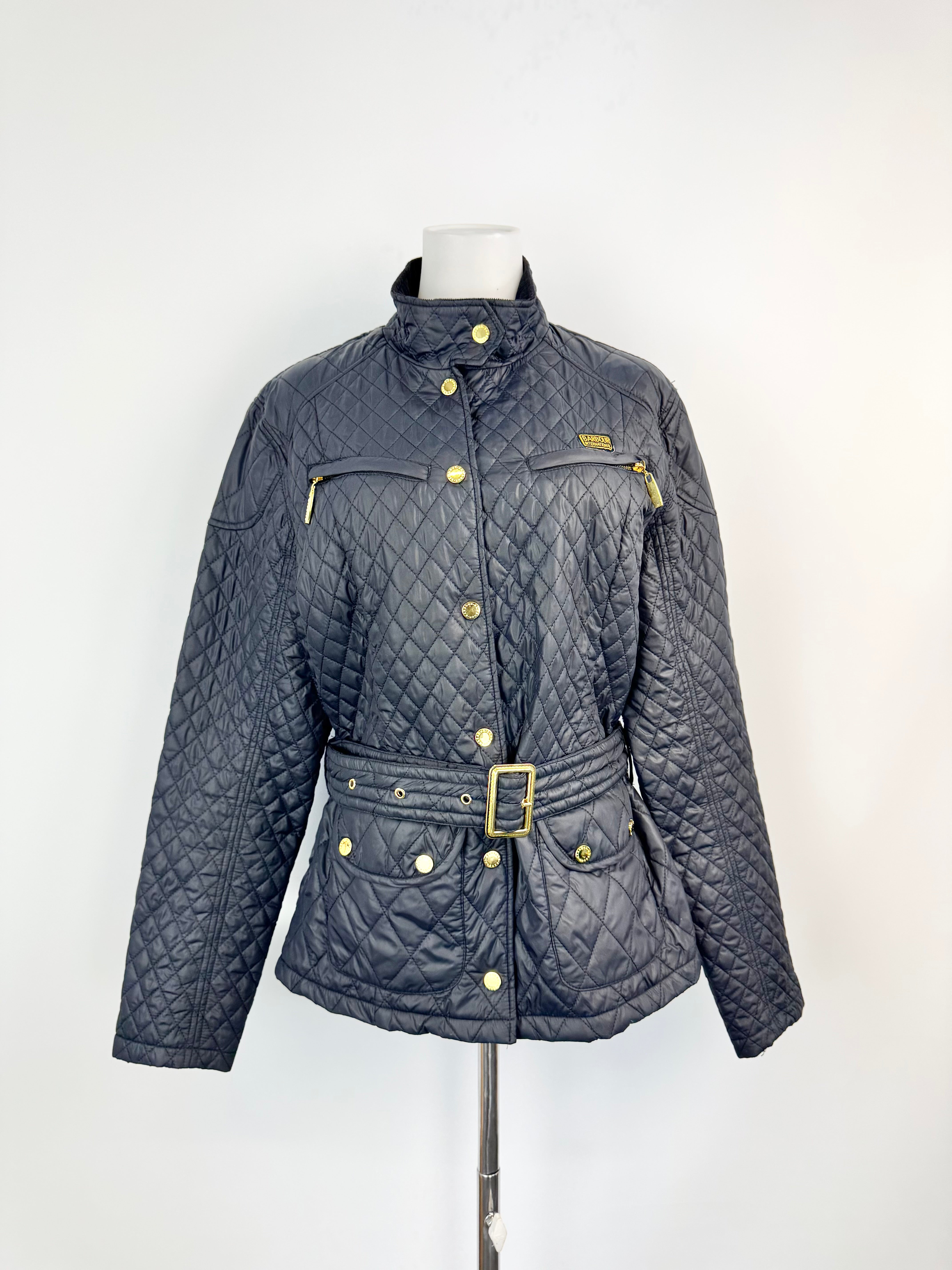 Quilted jacket with gold buttons and belt on a mannequin against a white background