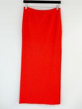 Bec + Bridge orange skirt on a hanger against a white background