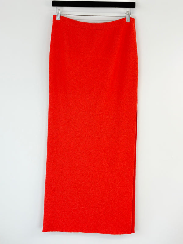 Bec + Bridge orange skirt on a hanger against a white background