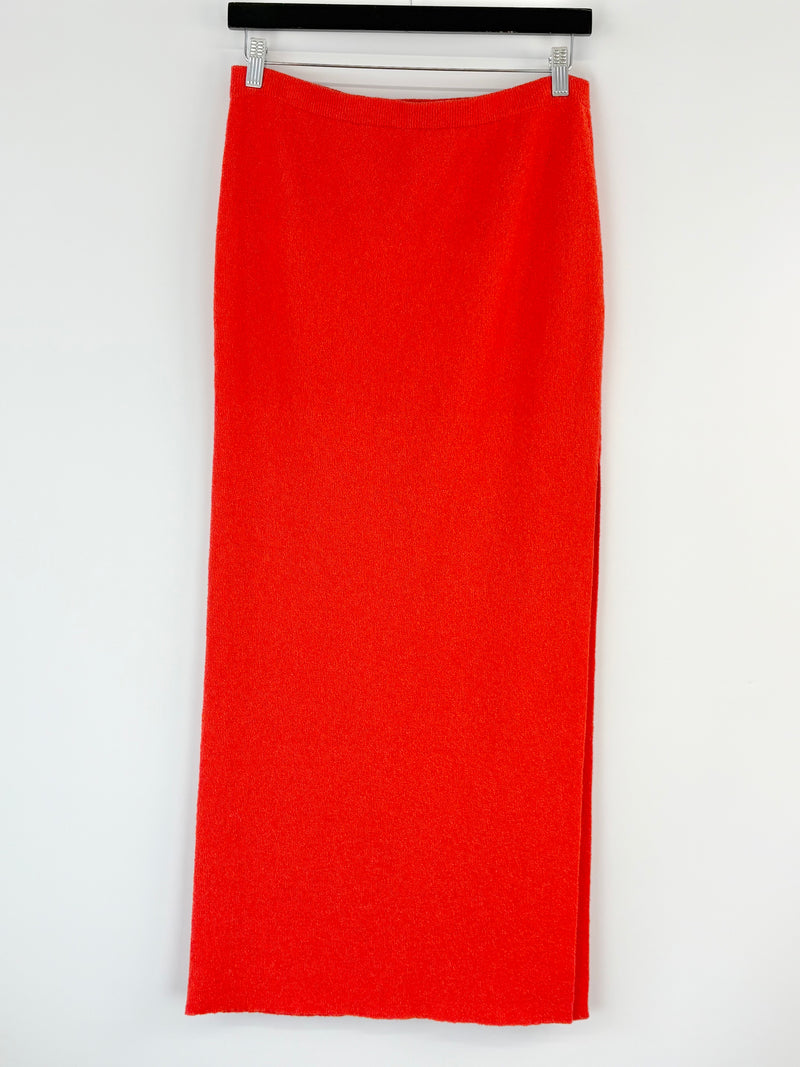 Bec + Bridge orange skirt on a hanger against a white background