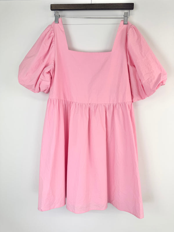 Pink dress with puff sleeves on a hanger against a white background