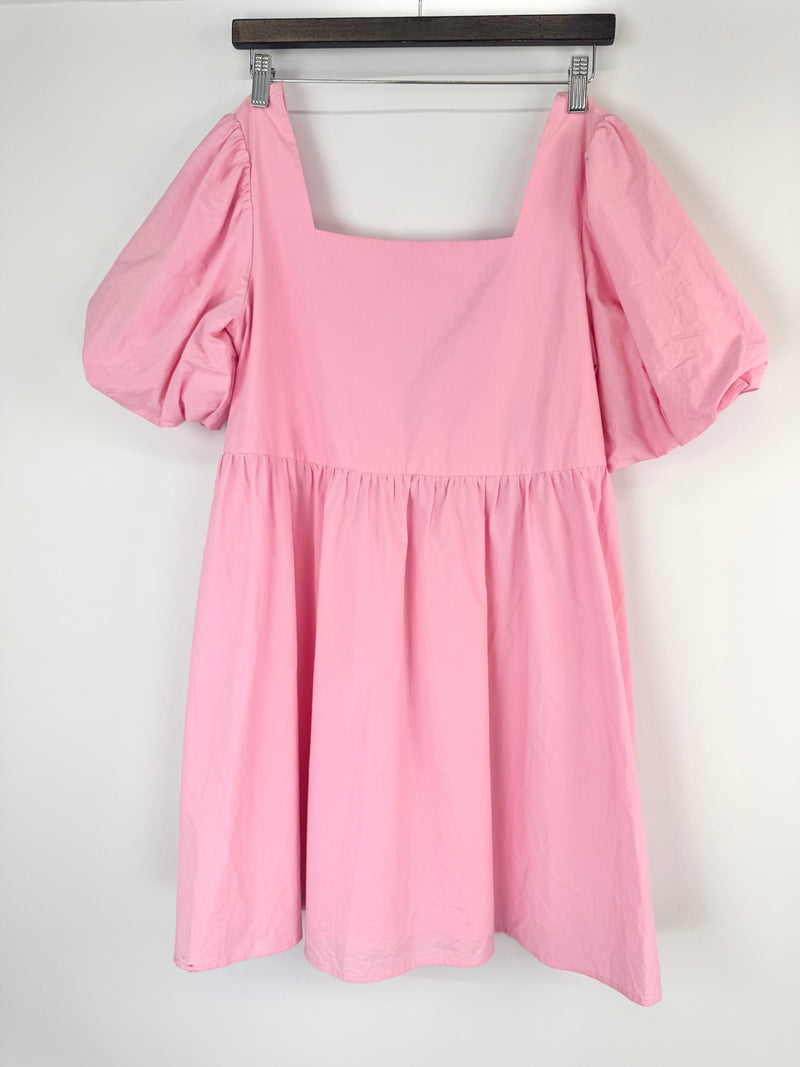 Pink dress with puff sleeves on a hanger against a white background