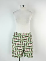 A pair of green, pink, and blue patterned shorts displayed on a mannequin.