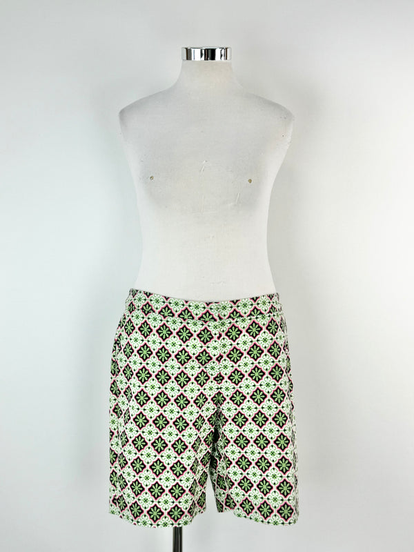A pair of green, pink, and blue patterned shorts displayed on a mannequin.
