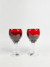 Two wine glasses with red liquid on a white background