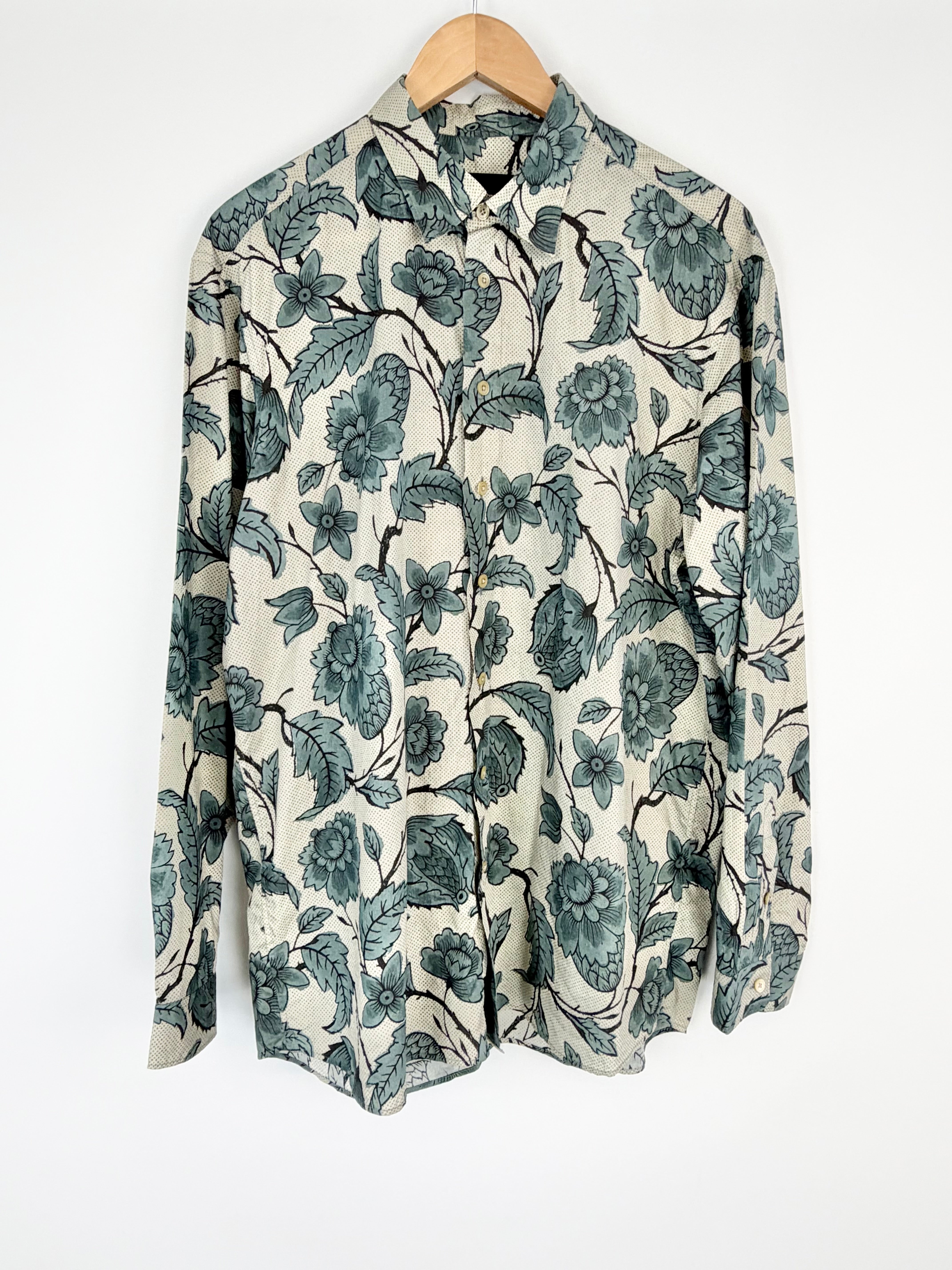 Floral patterned shirt on a wooden hanger against a white background