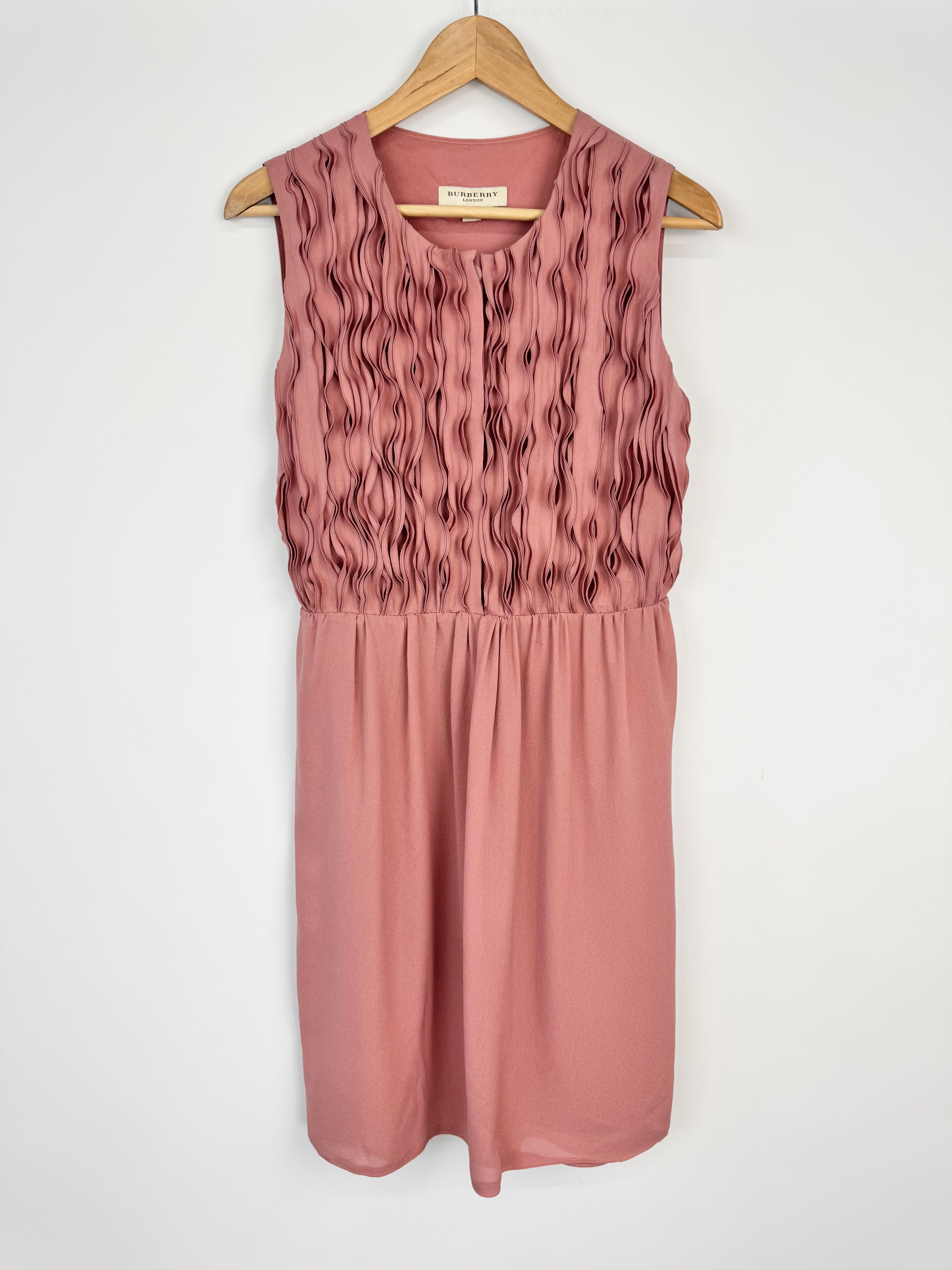 Pink dress on a hanger against a white background