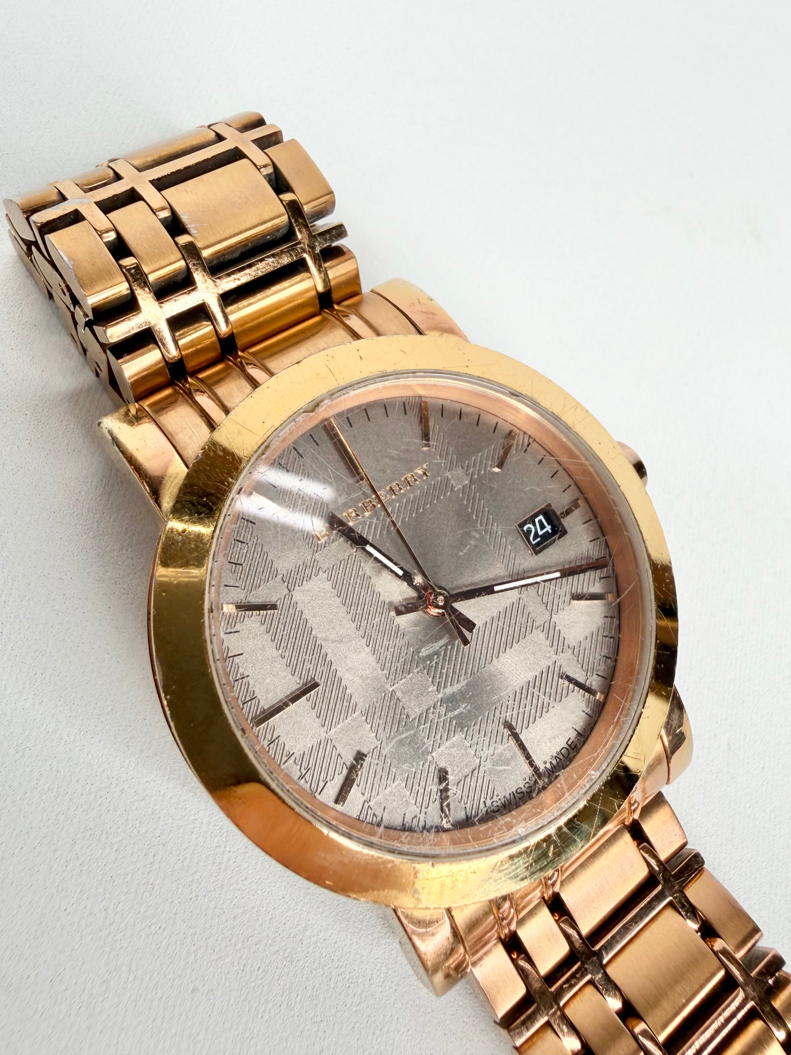 Gold wristwatch with a silver face on a light gray background