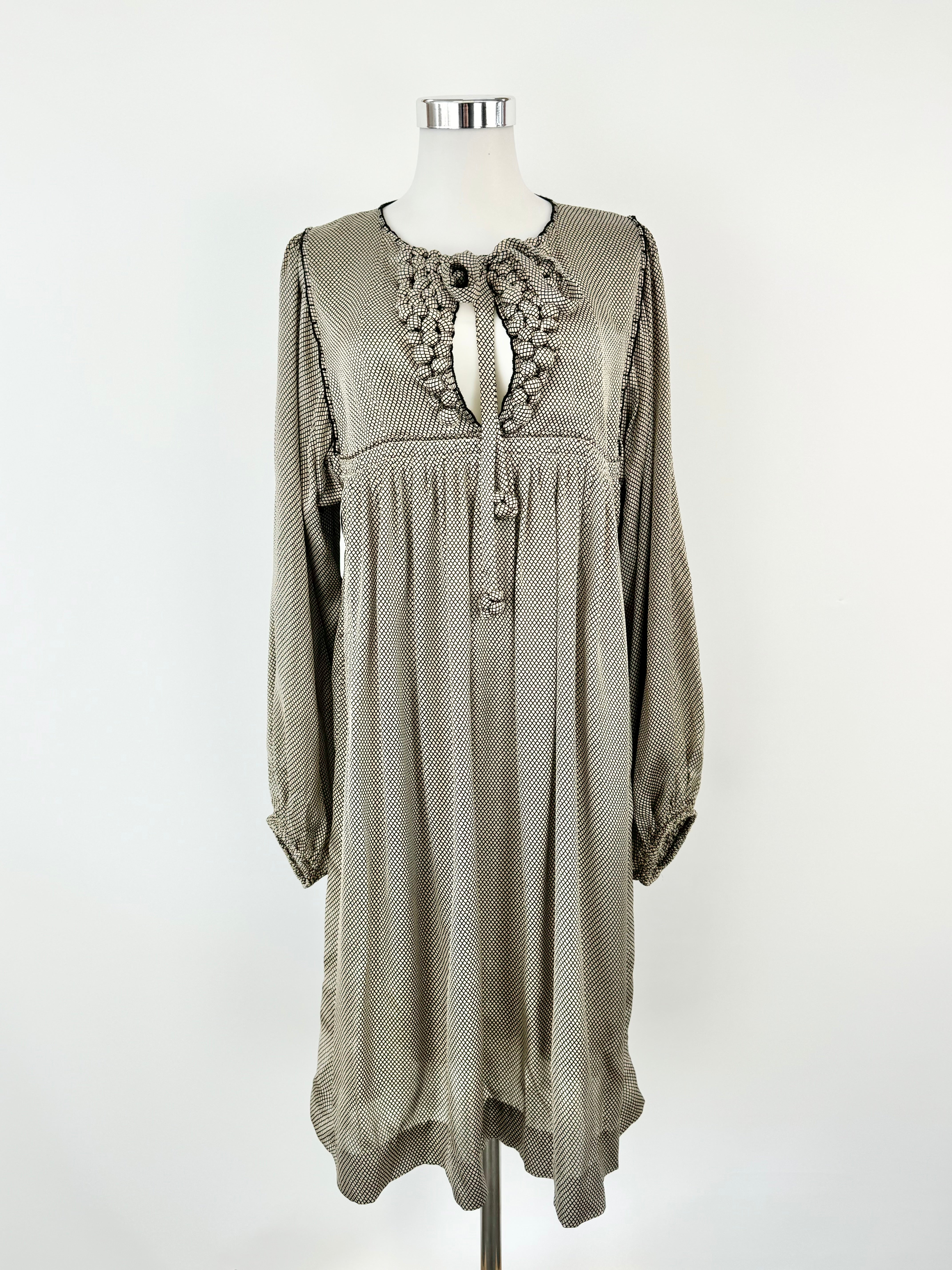 A cream and black grid pattern silk dress with long sleeves, a high rounded neckline, and decorative 'bobbles' on the front bust, displayed on a mannequin.