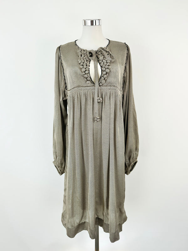 A cream and black grid pattern silk dress with long sleeves, a high rounded neckline, and decorative 'bobbles' on the front bust, displayed on a mannequin.