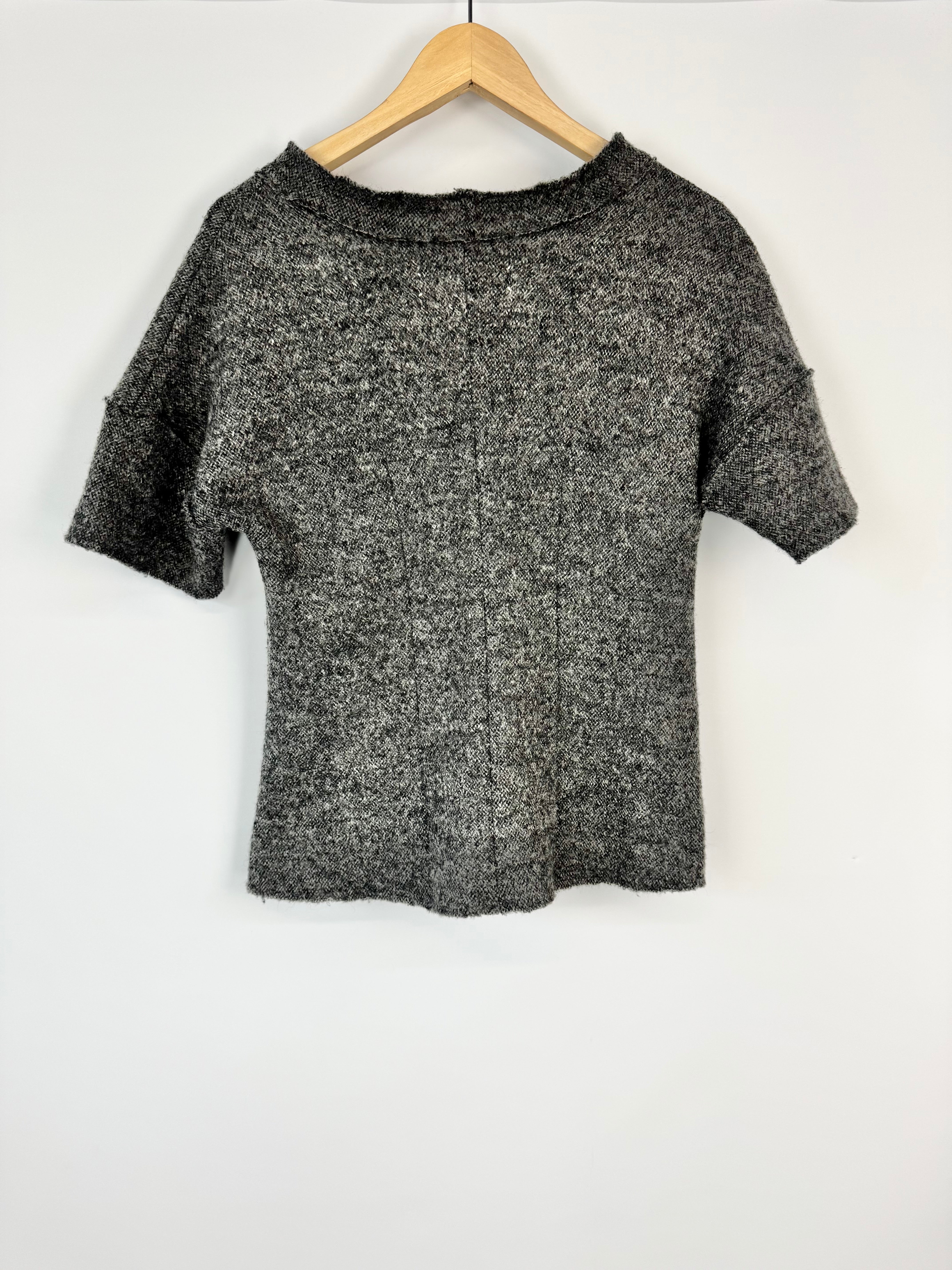 Black textured shirt on a wooden hanger against a white background