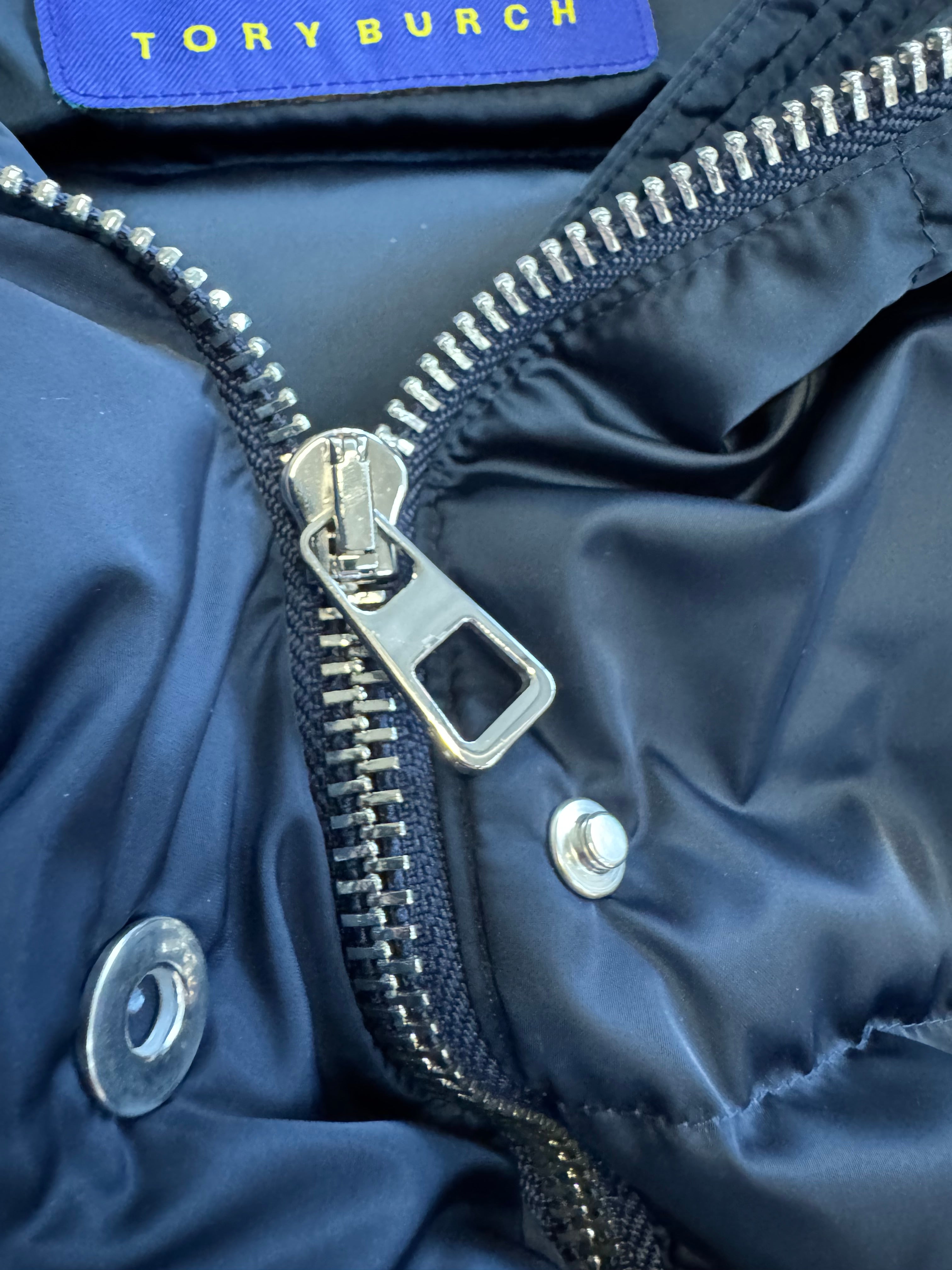 Close-up of a navy blue jacket zipper with a Tory Burch label.