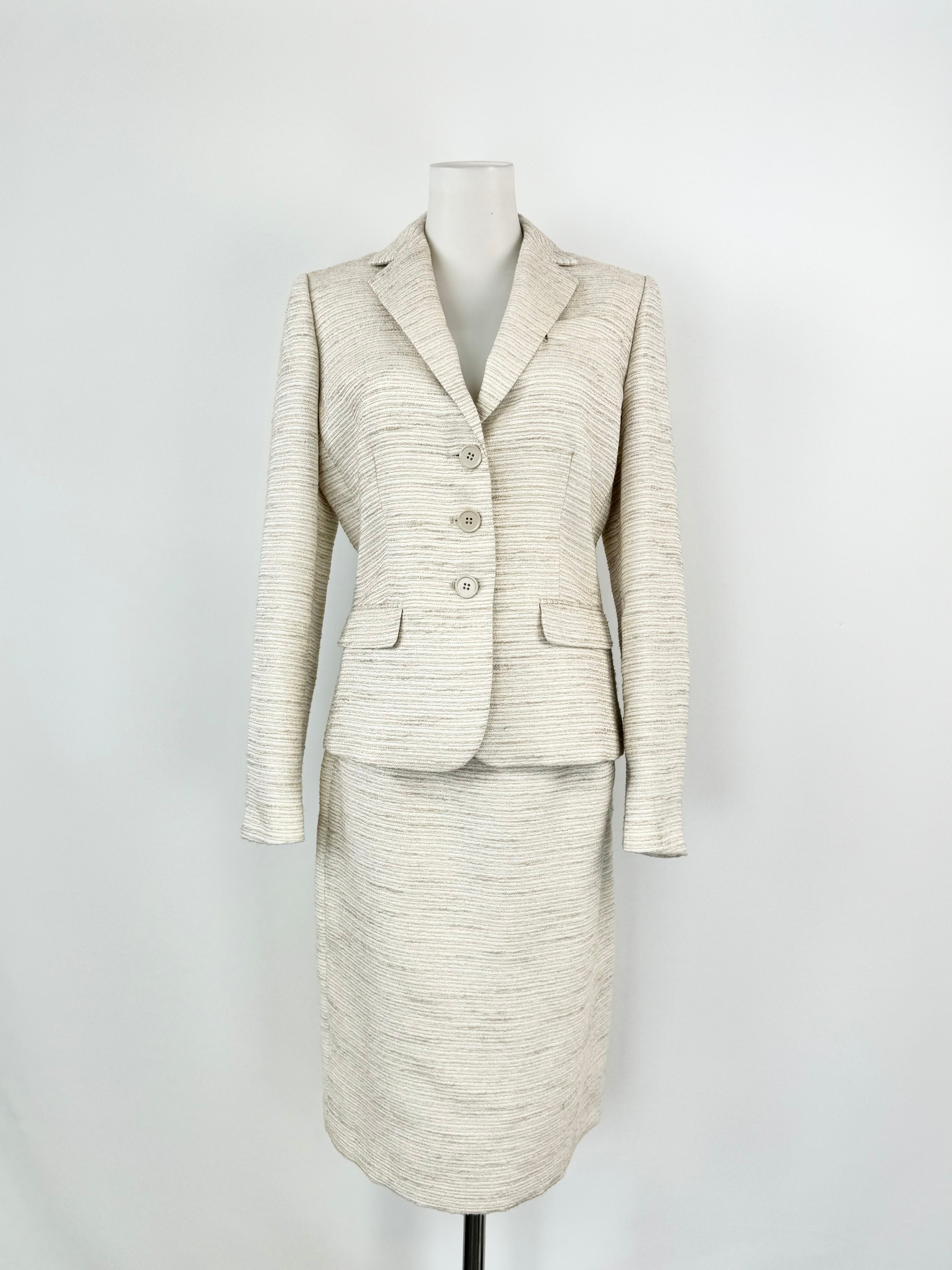 A Calvin Klein silver, white, and cream woven two-piece suit consisting of a blazer and a pencil skirt, displayed on a mannequin.