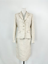 A Calvin Klein silver, white, and cream woven two-piece suit consisting of a blazer and a pencil skirt, displayed on a mannequin.