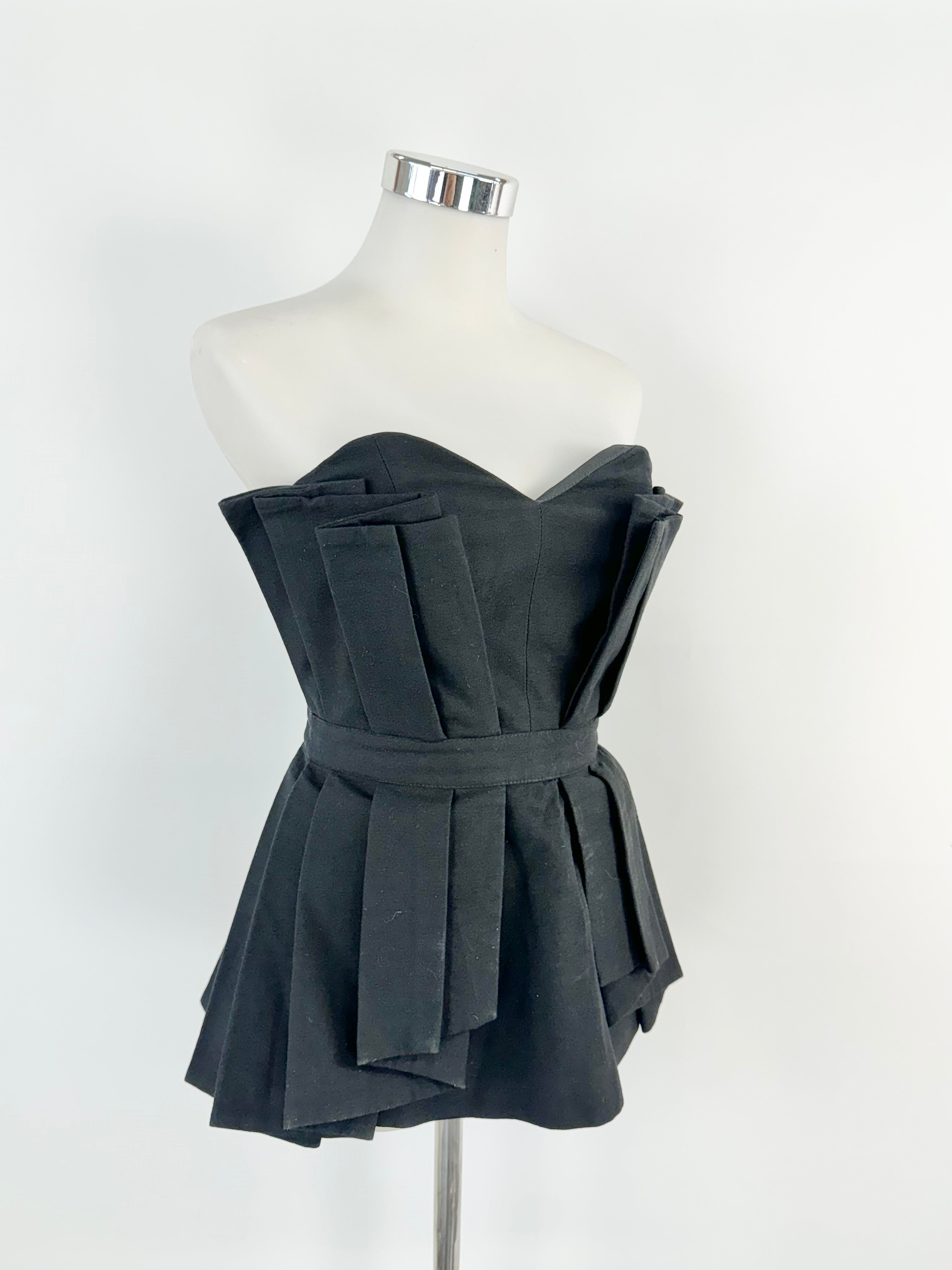 A black layered bustier displayed on a mannequin, featuring a structured fit and a zipper at the back.