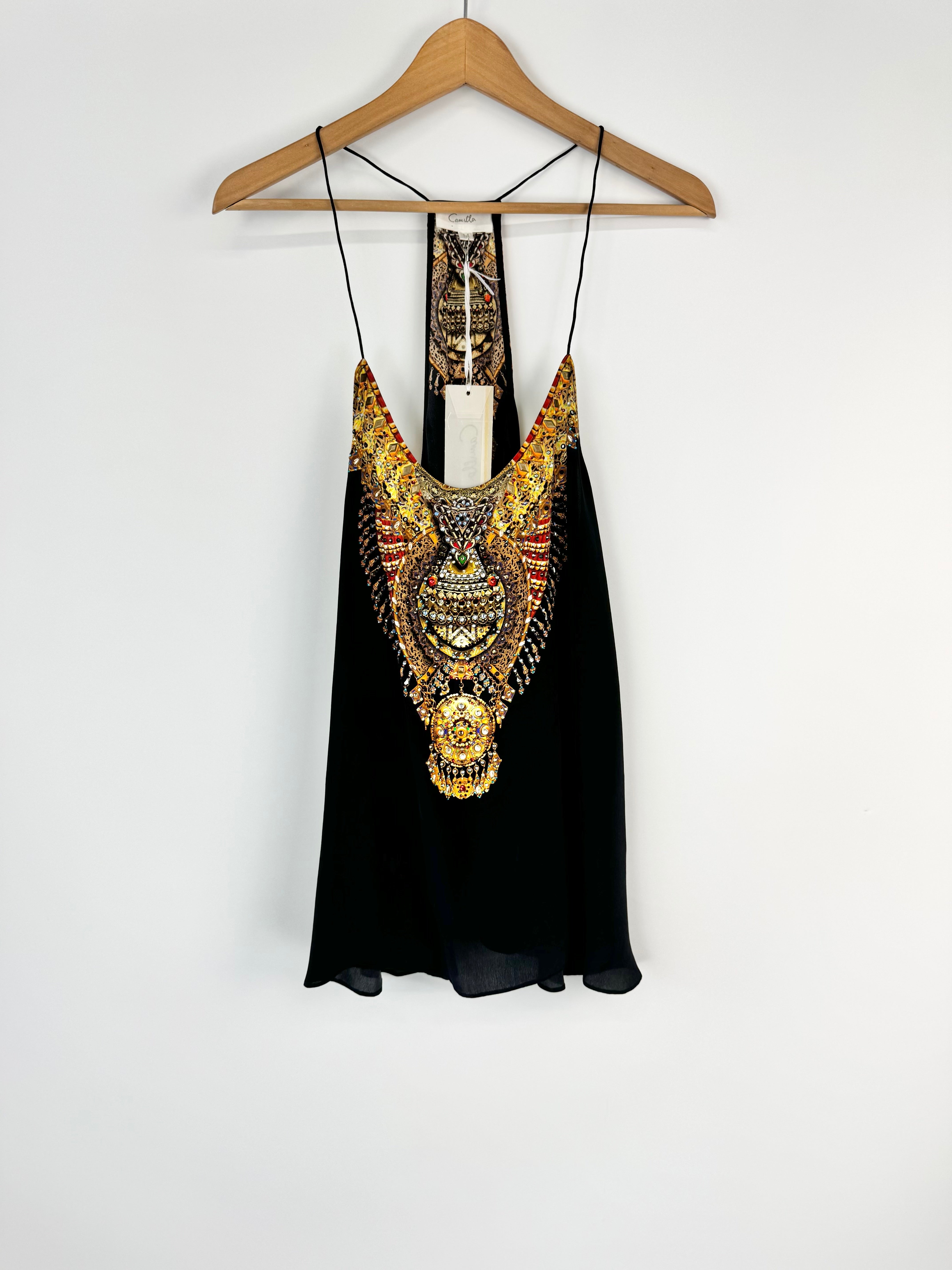 Black top with gold embellishments on a hanger against a white background