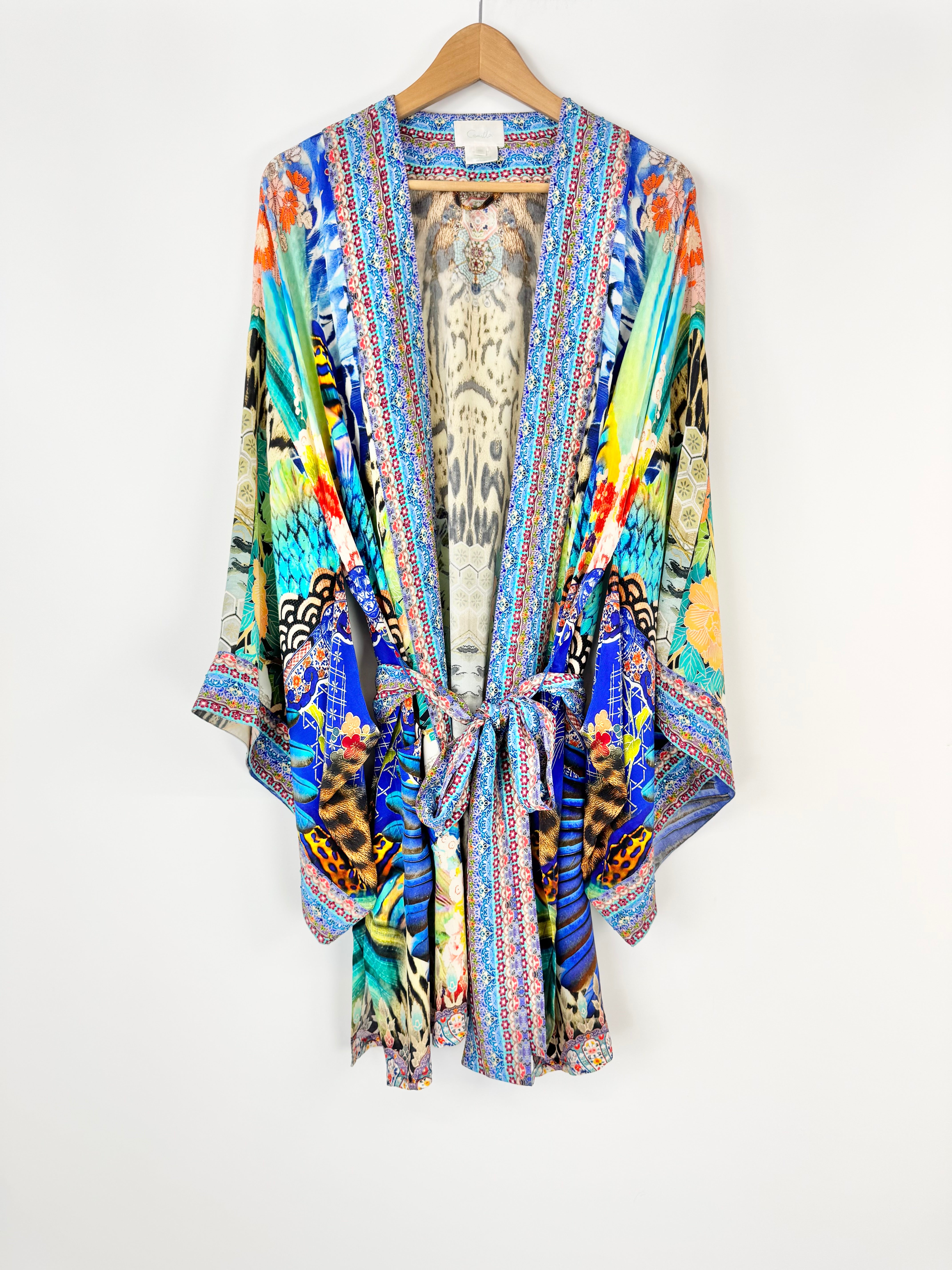 Colorful kimono-style jacket with a pattern on a hanger against a white background
