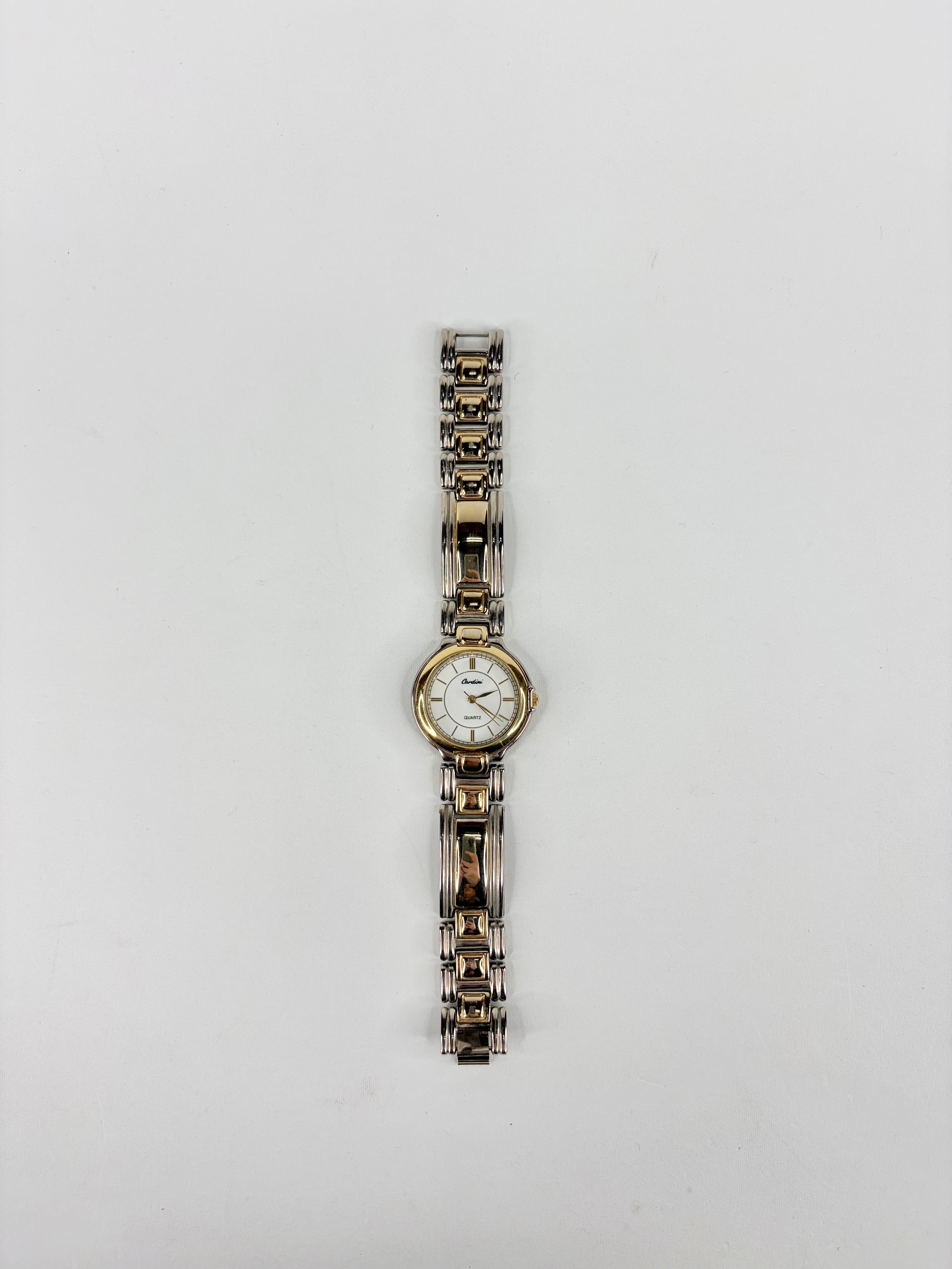 Silver watch with a white face on a light gray background